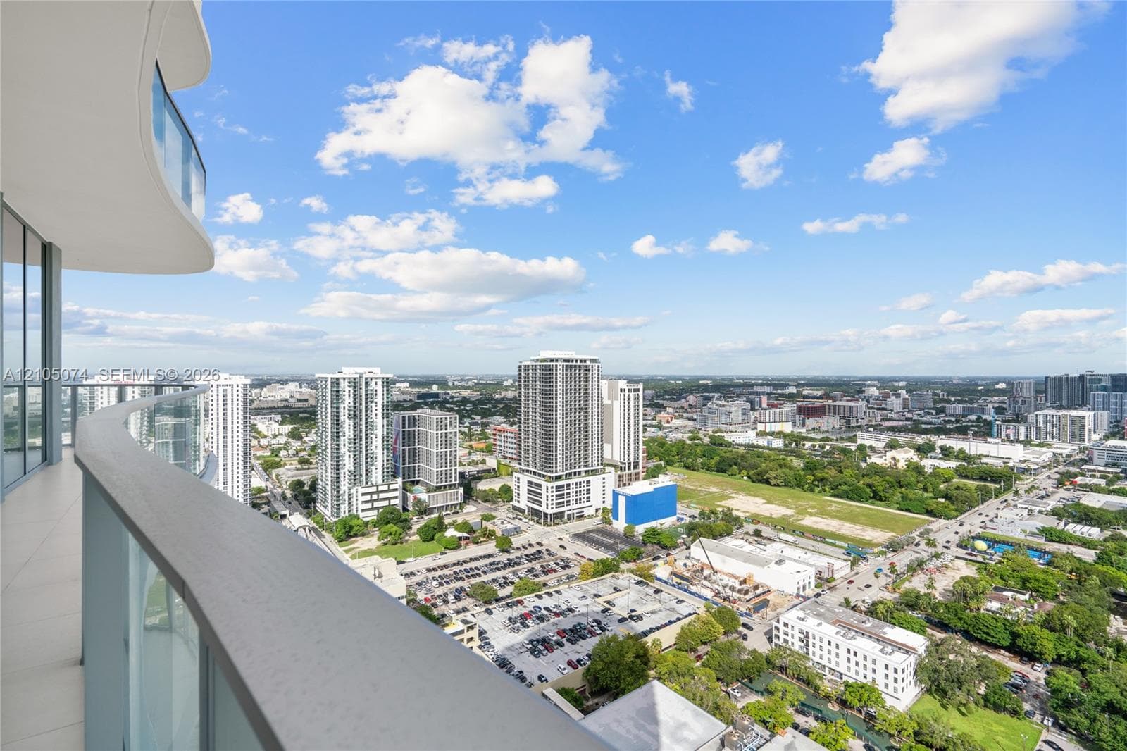 Floor-to-ceiling windows, sliding glass door, private balcony with metal railing, and large-format tile flooring