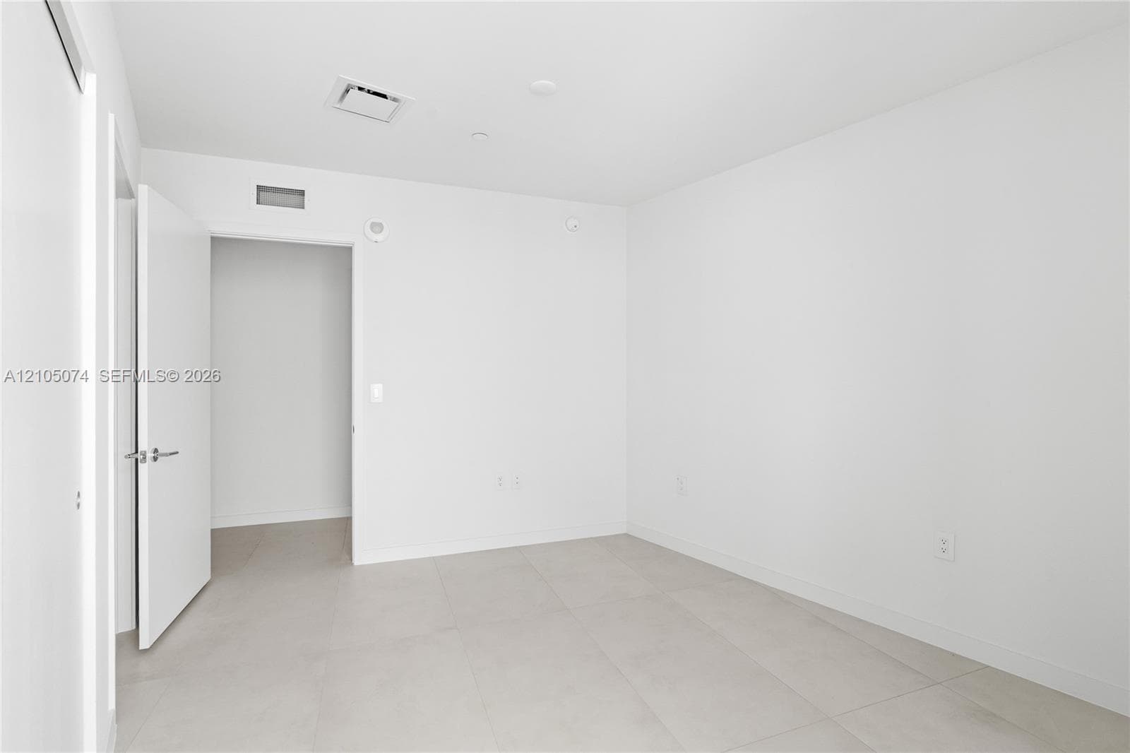Floor-to-ceiling windows, private balcony with metal railing, large-format tile flooring, recessed lighting, and expansive city skyline scenery