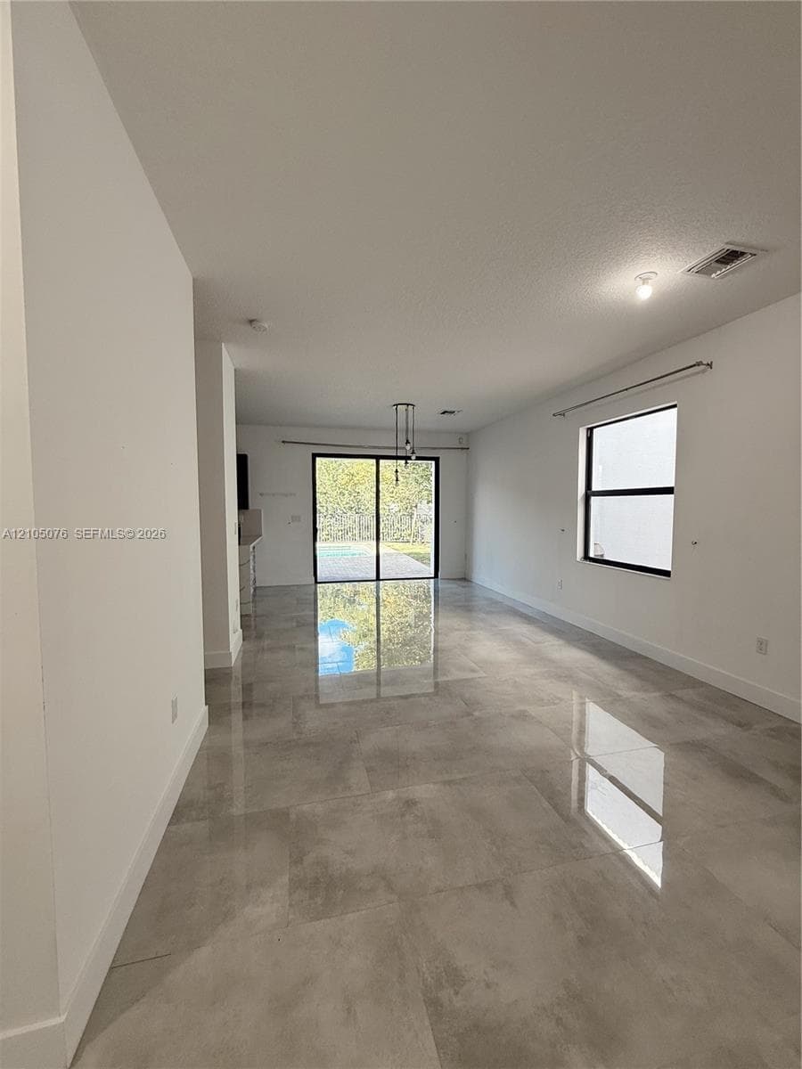 Open-concept interior featuring large-format tile flooring, recessed lighting, and sliding glass doors leading to the exterior