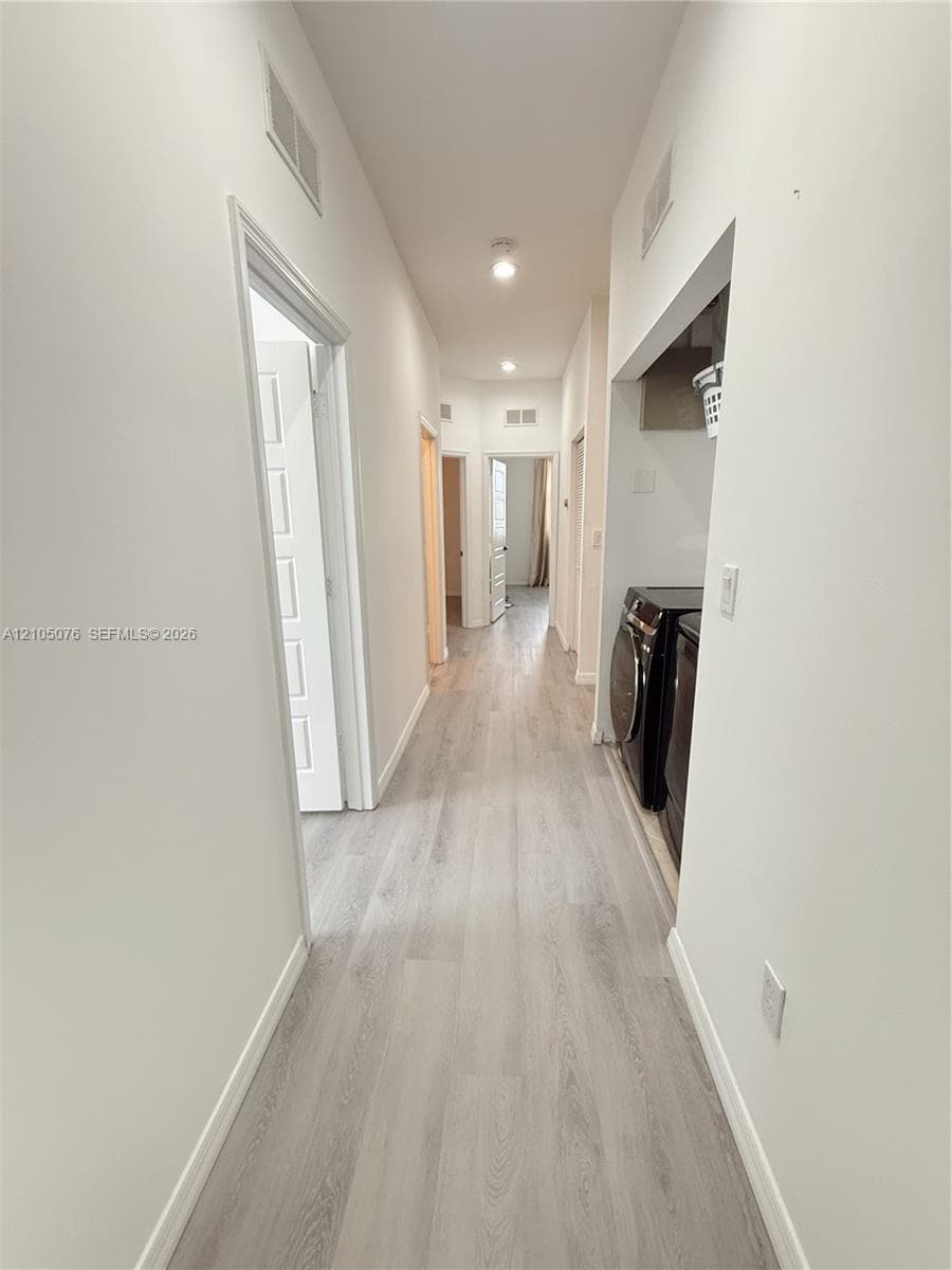 Hallway featuring wood-finish flooring, recessed ceiling lighting, and multiple panel doors