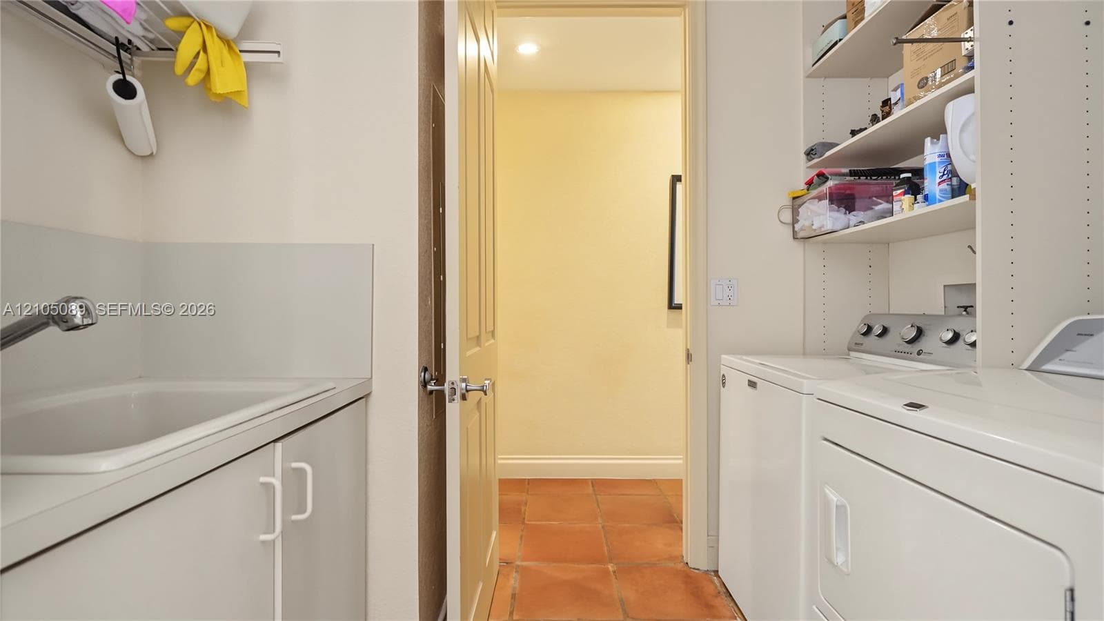 Utility room featuring a built-in sink with cabinetry, ceramic tile flooring, and integrated shelving