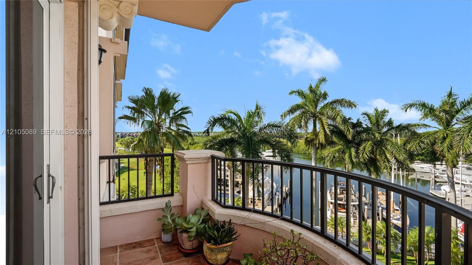 Covered balcony featuring terracotta-style tile flooring, black metal railing, and decorative stone-finish columns