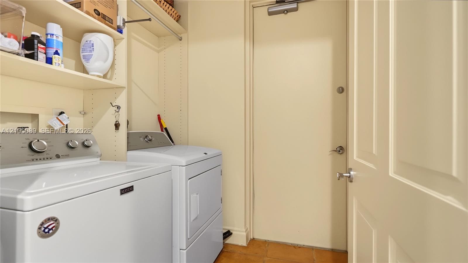 Laundry space featuring built-in shelving, a dedicated hanging rod, and tile flooring