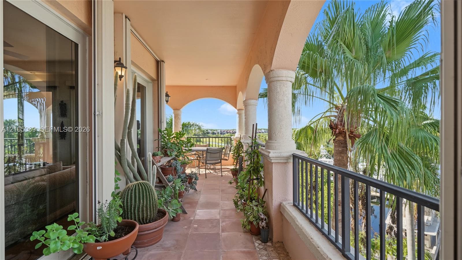 Covered balcony featuring tile flooring, structural masonry columns, arched architecture, and metal railings