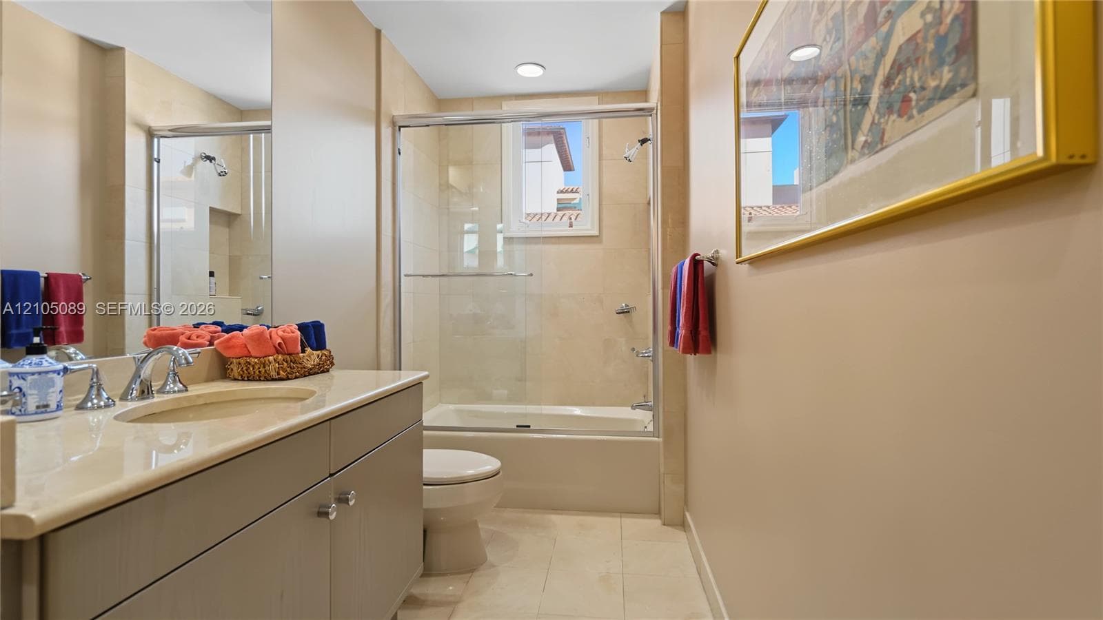 Bathroom featuring a vanity with a light-toned countertop, integrated basin, recessed lighting, and a bathtub with a glass enclosure and wall-tiled surround