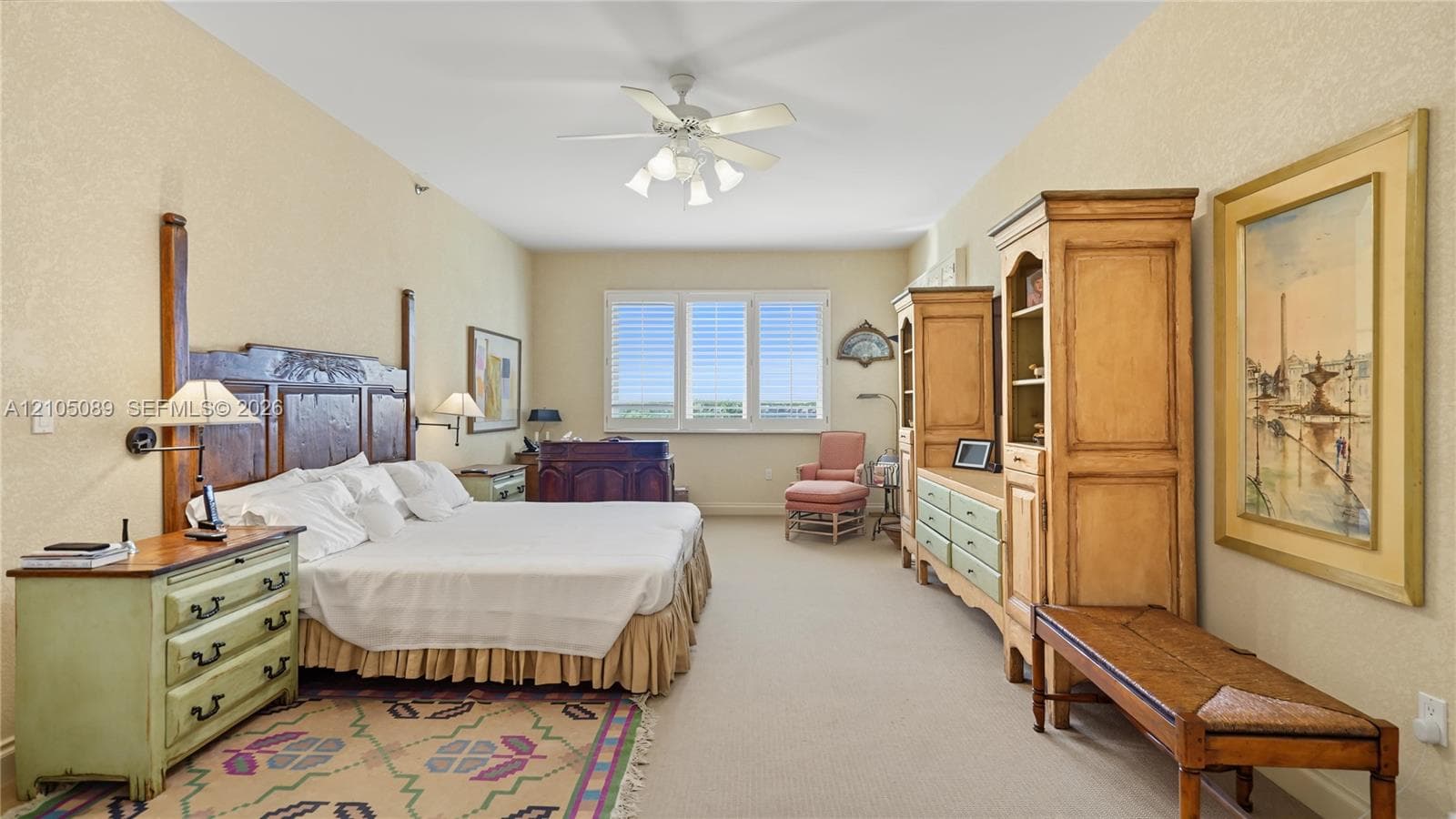 Neutral interior space featuring high ceilings with a central ceiling fan and white window shutters