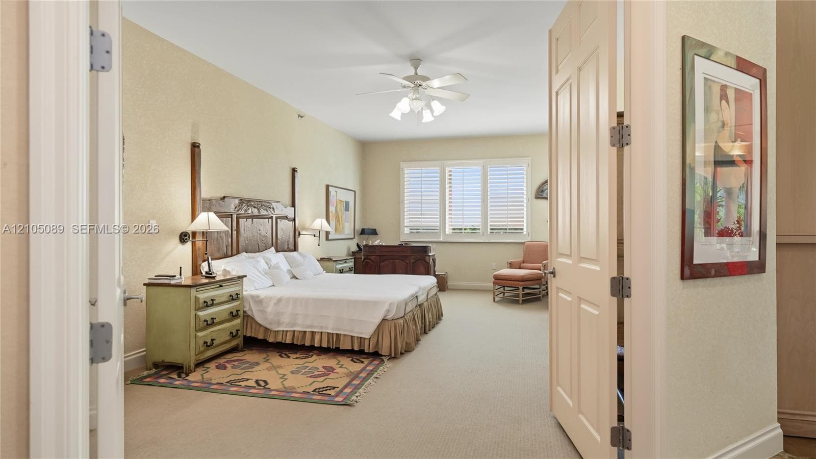 Spacious room featuring carpeting, multi-pane windows with integrated shutters, a central ceiling fan with multi-light fixture, and double-hinged doors