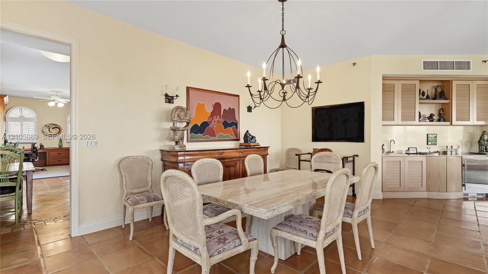 Dining area featuring tile flooring, a multi-arm metal chandelier, and a built-in cabinetry unit with an integrated sink and countertop