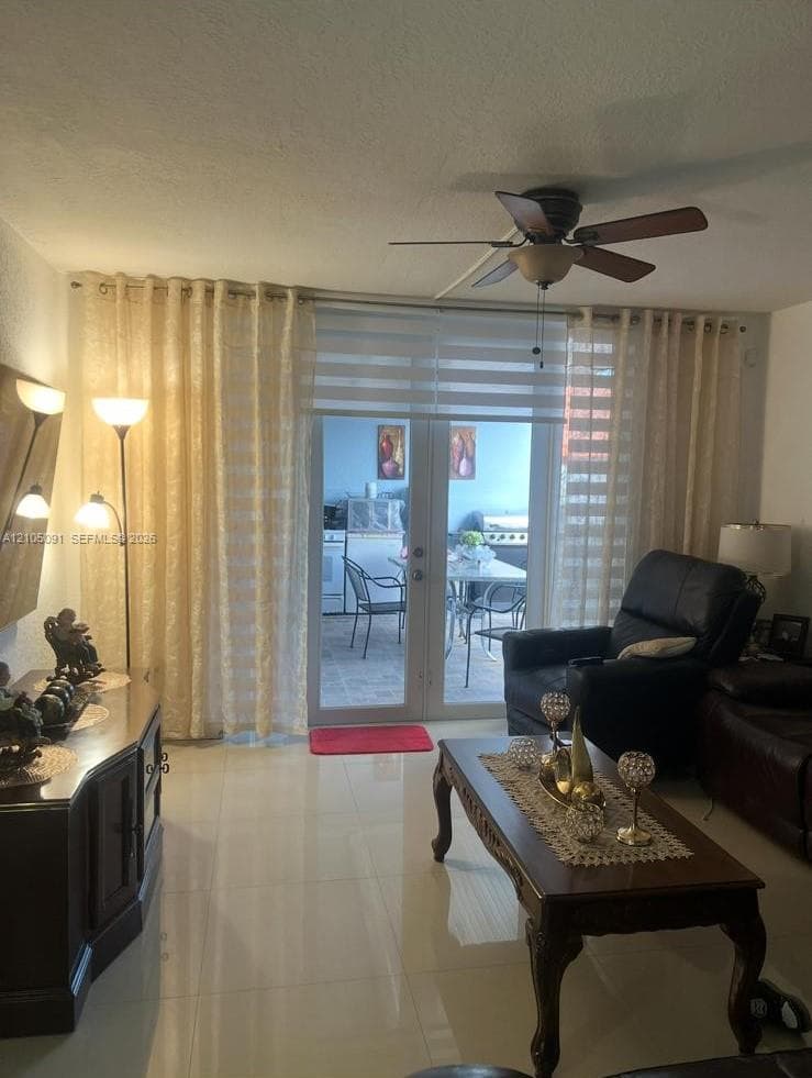 Living area featuring large-format tile flooring and double glass-paned doors with integrated blinds leading to the exterior