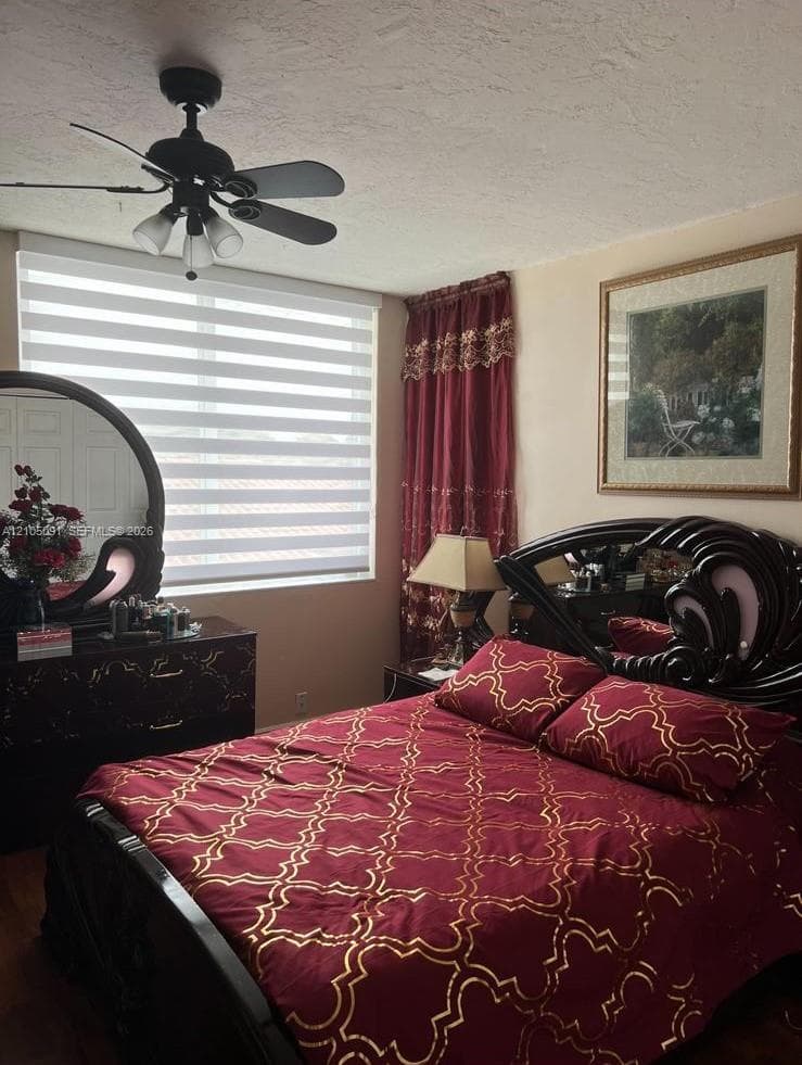 Textured ceiling, matte black ceiling fan with integrated lighting, and horizontal sheer-paneled window shades