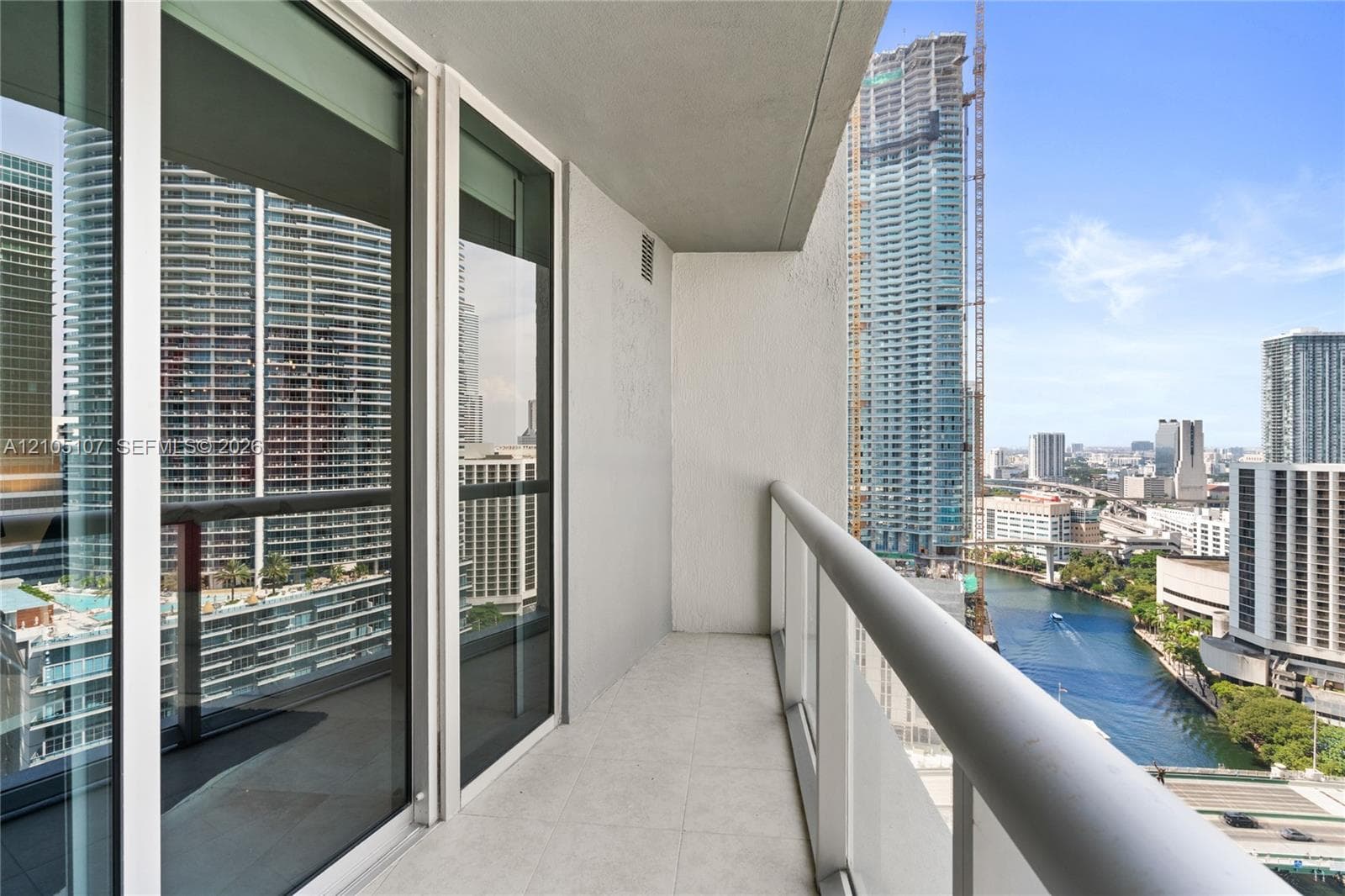 Balcony with tiled flooring, clear glass railing, and sliding glass doors