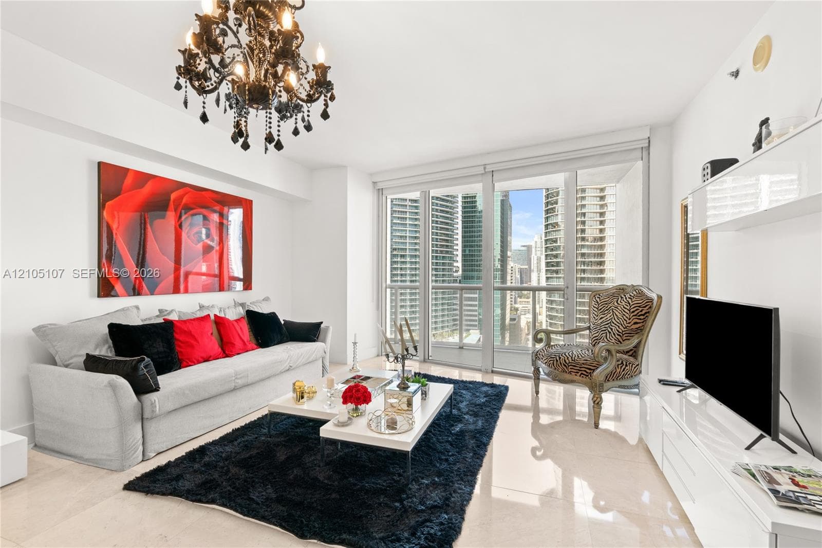Chandelier lighting, full-height windows, balcony access, built-in shelving, and light-toned tile flooring