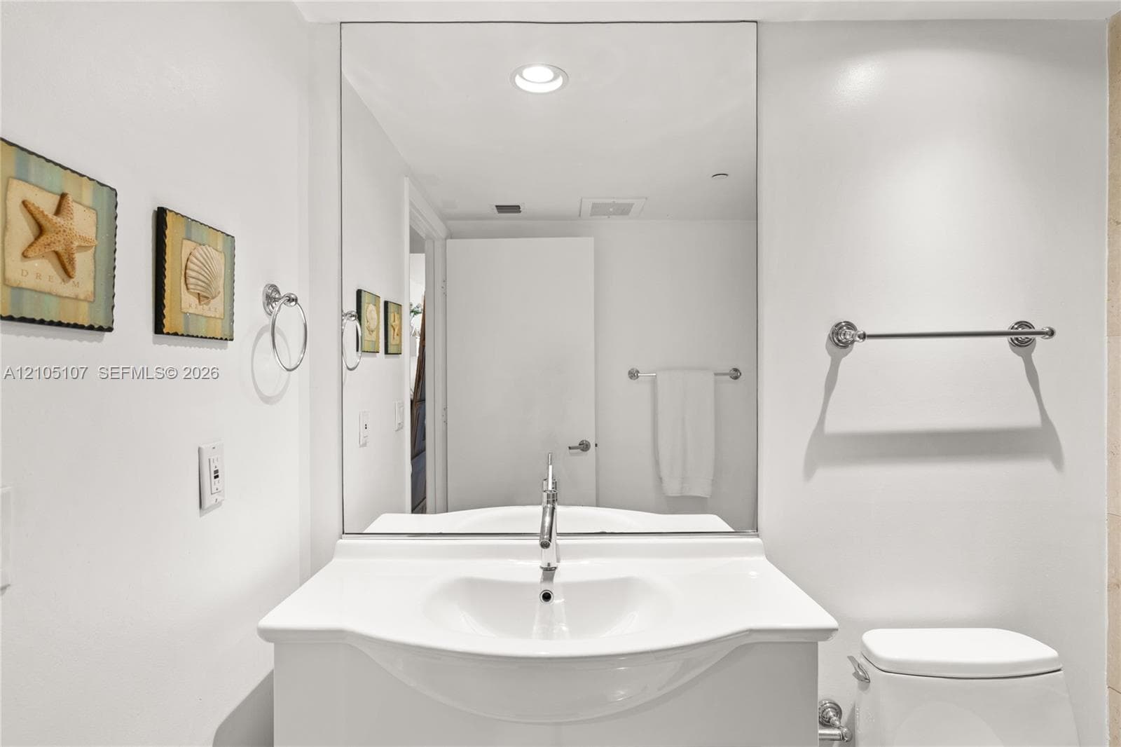 Recessed ceiling lighting illuminates a vanity with an integrated sink and chrome faucet