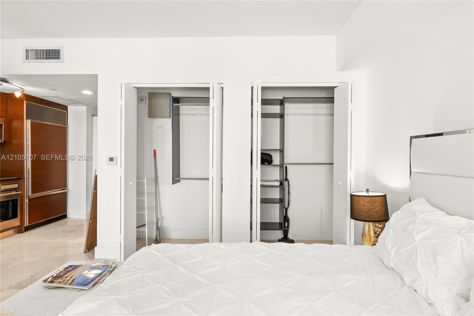 Two built-in closets with bi-fold doors, recessed lighting, and a white upholstered headboard