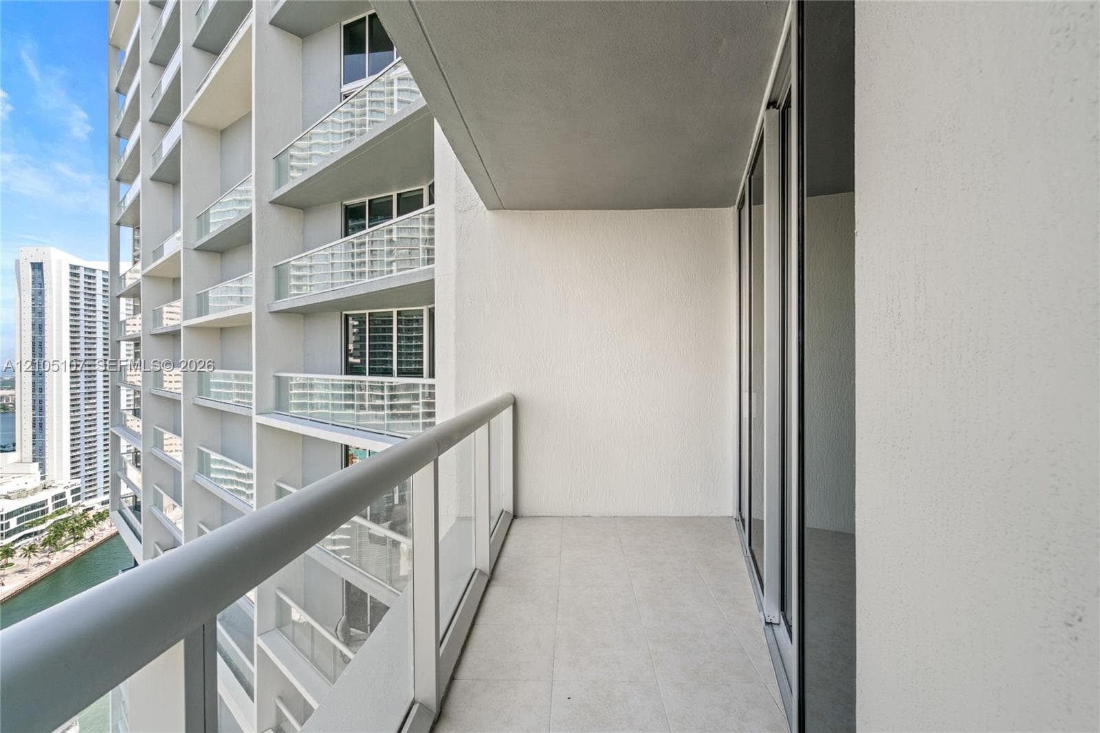 Private balcony with a glass and metal railing, offering urban and water scenery