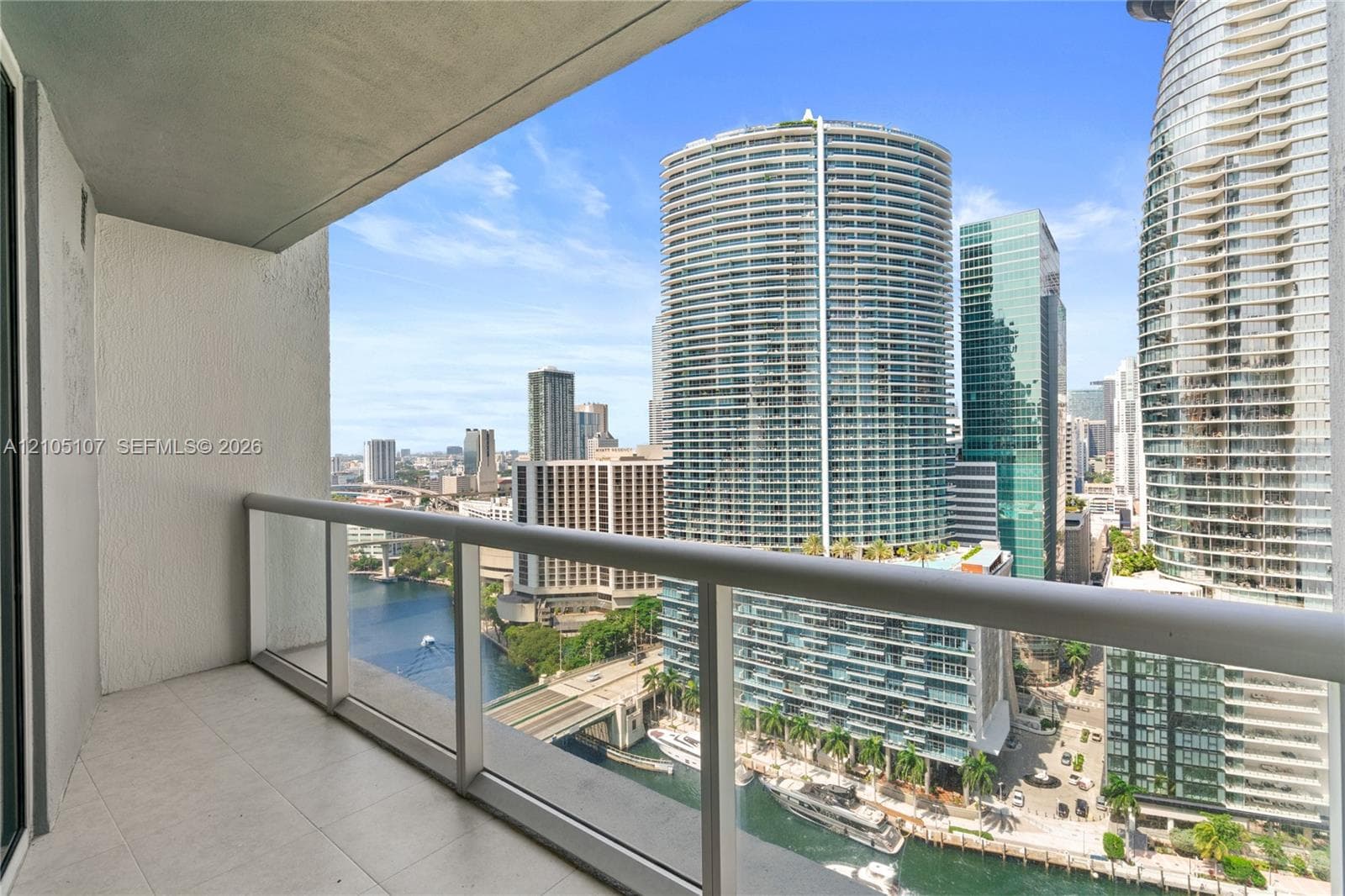 Balcony featuring tile flooring, glass panel railing, and cityscape with water