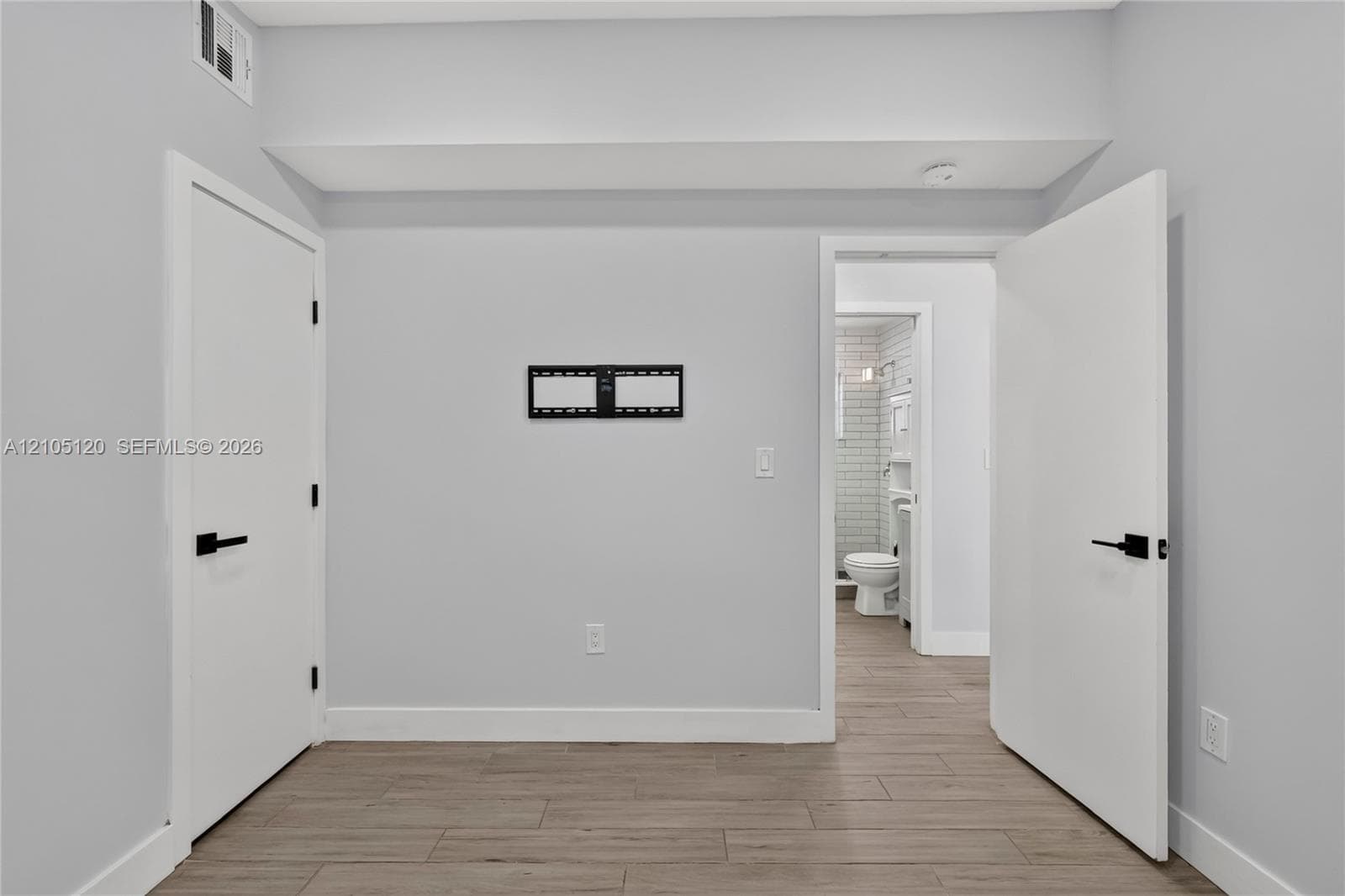Interior space featuring wood-finish flooring, matte black door hardware, and smooth walls with neutral paint