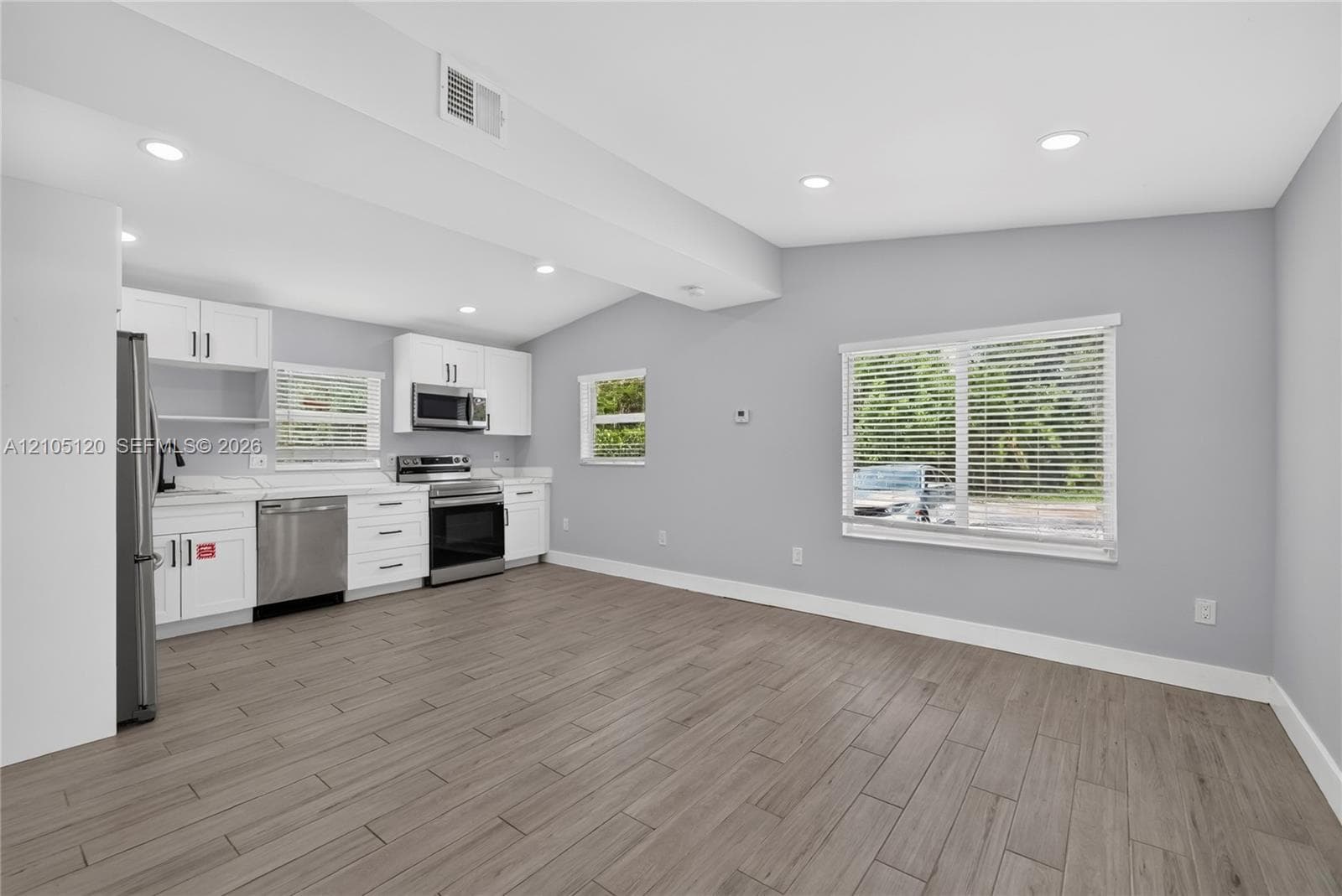 Kitchen featuring white cabinetry, stainless steel appliances, wood-finish flooring, and recessed ceiling lighting