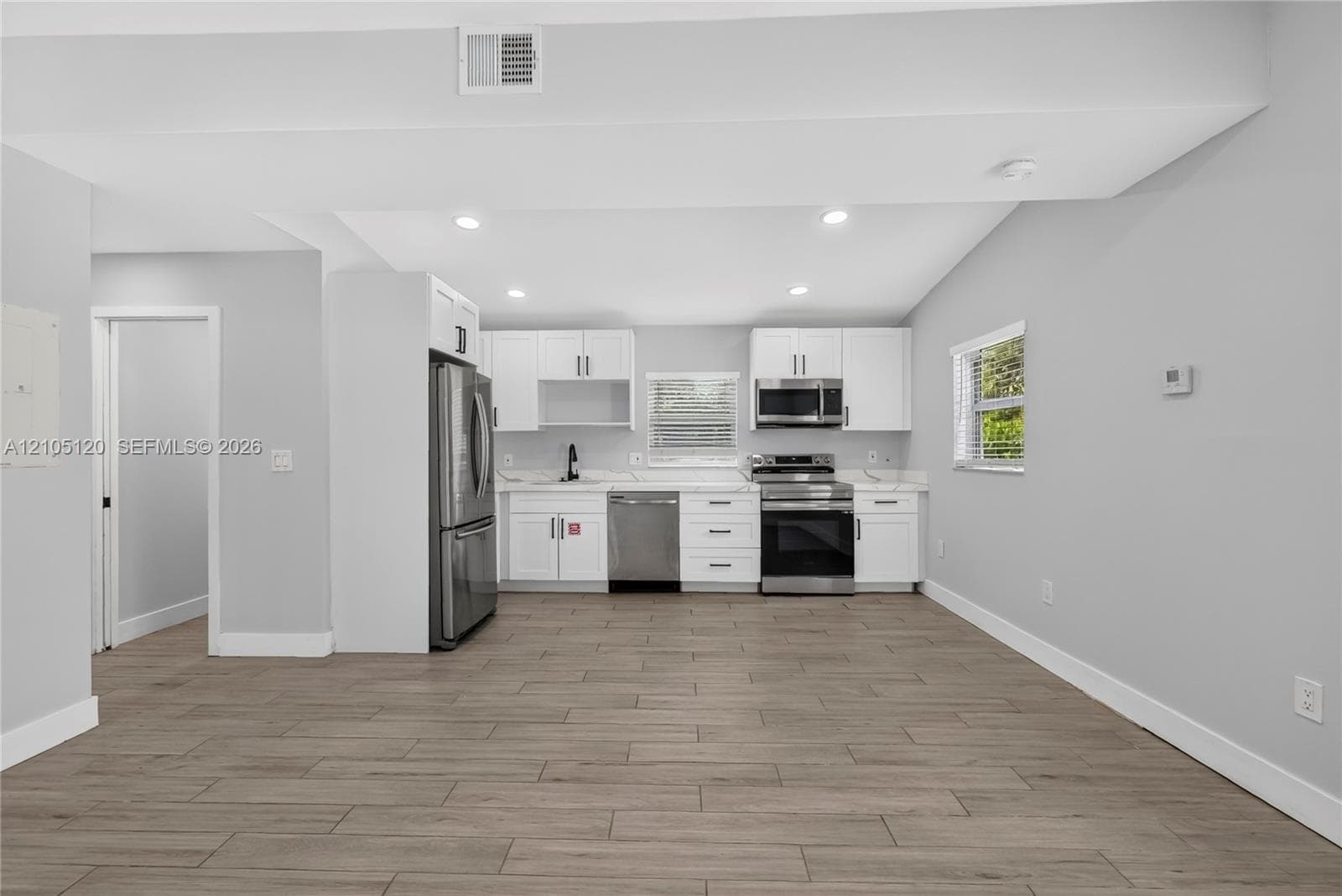 Kitchen featuring white shaker-style cabinetry, wood-finish flooring, recessed lighting, and stainless steel appliances including a microwave, dishwasher, and stove