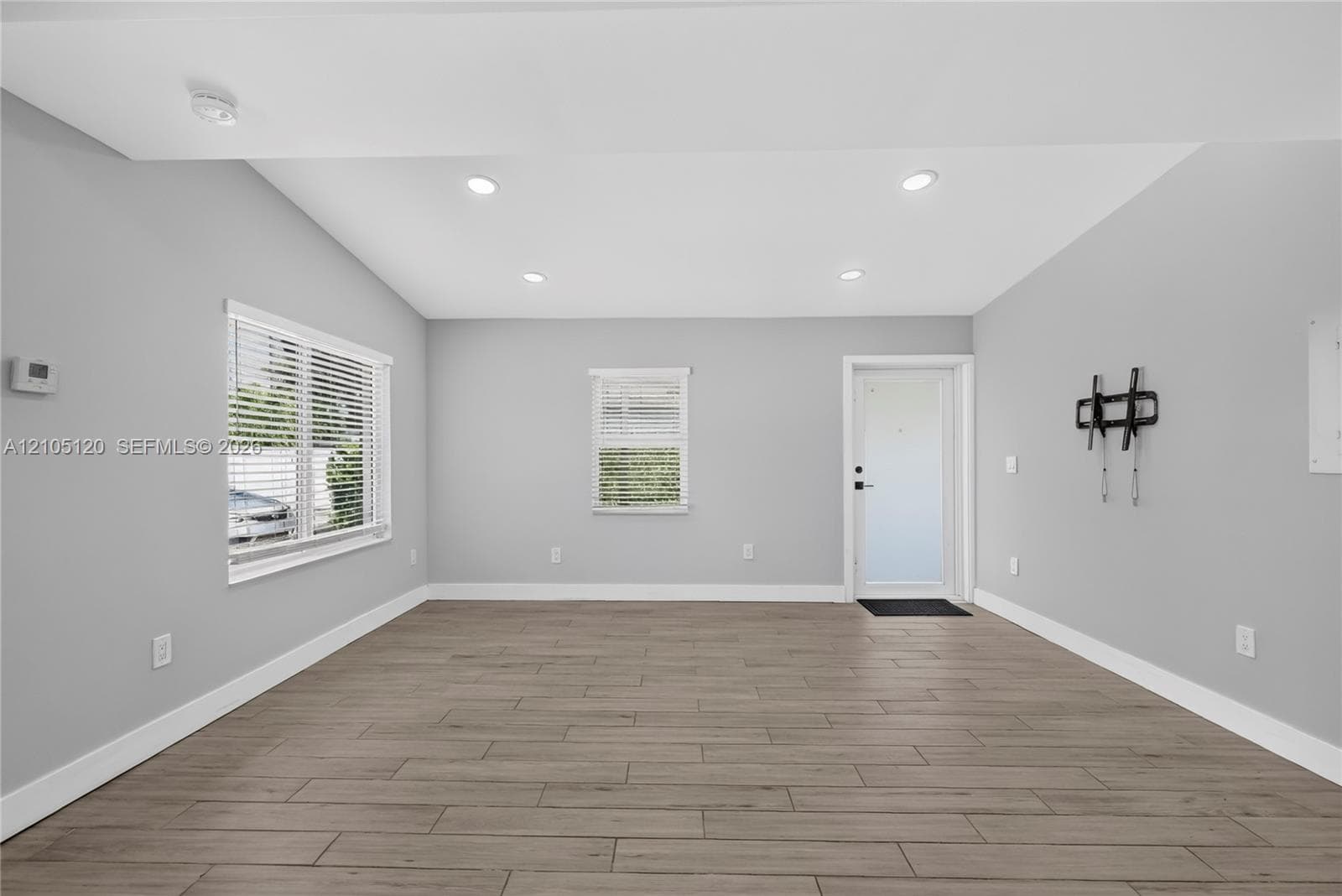 Neutral-toned interior featuring wood-finish tile flooring, recessed lighting, and multiple windows with white window blinds