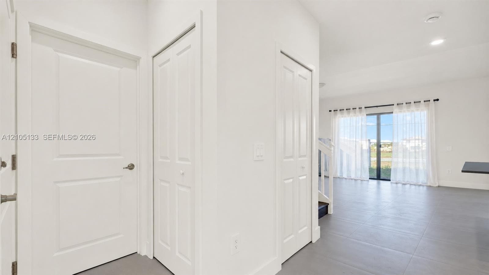 Neutral color palette, recessed lighting, tile flooring, sliding glass doors, and a staircase with white balusters