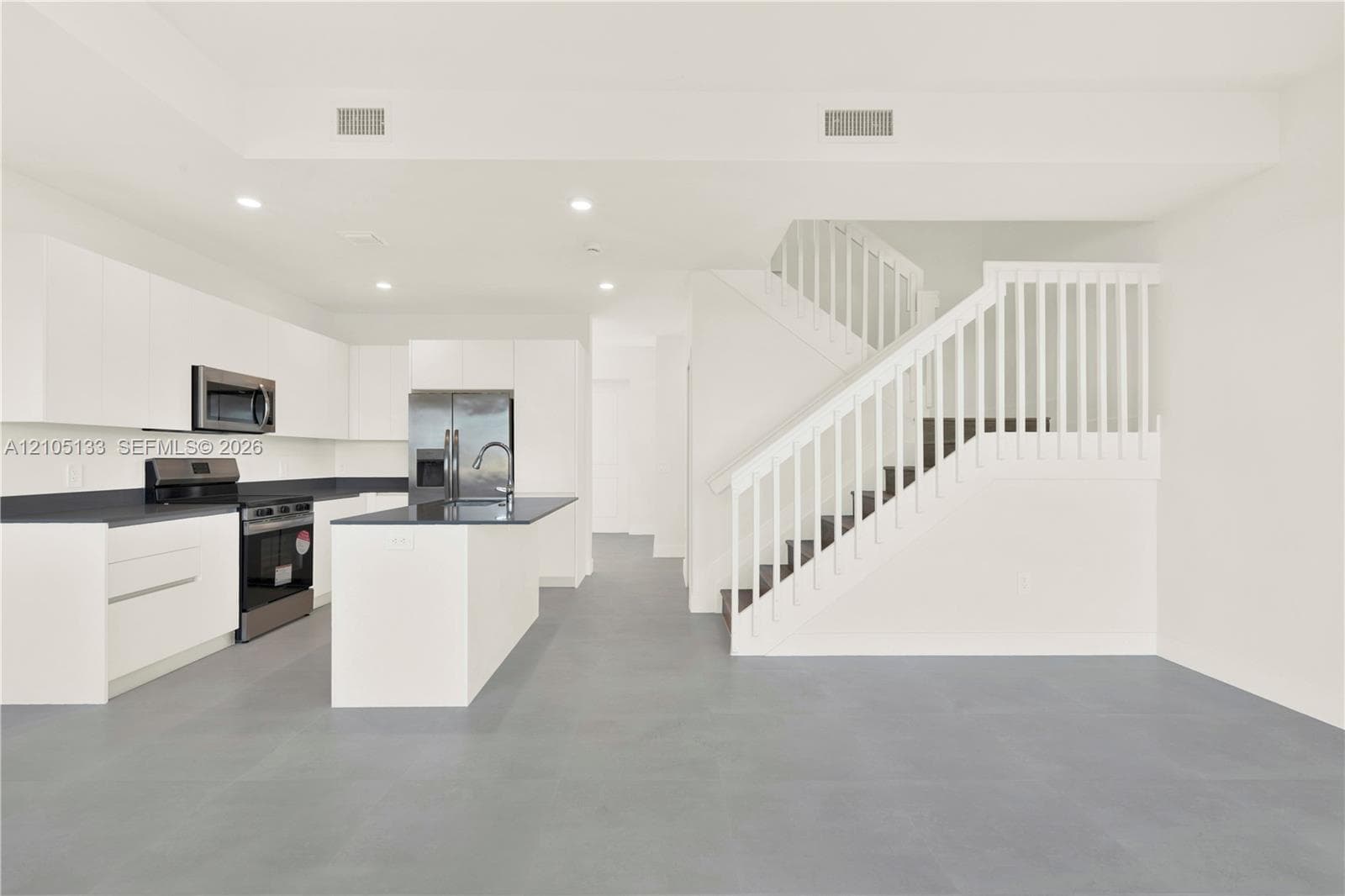Modern kitchen featuring white cabinetry, dark countertops, and stainless steel appliances