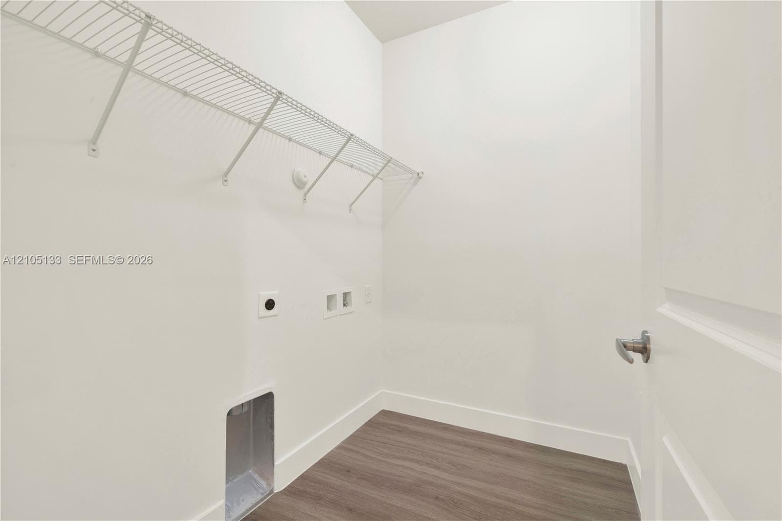 Laundry area with wood-finish flooring, white walls, and built-in wire shelving