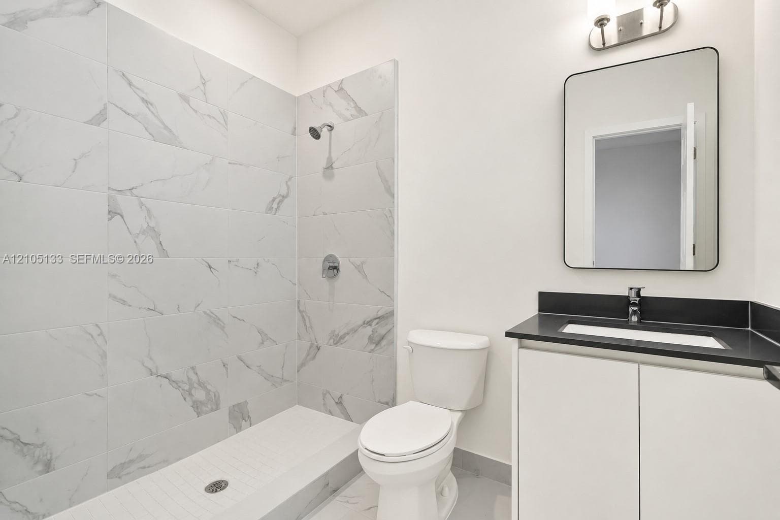Shower with white tile surround, a built-in bench, and chrome fixtures