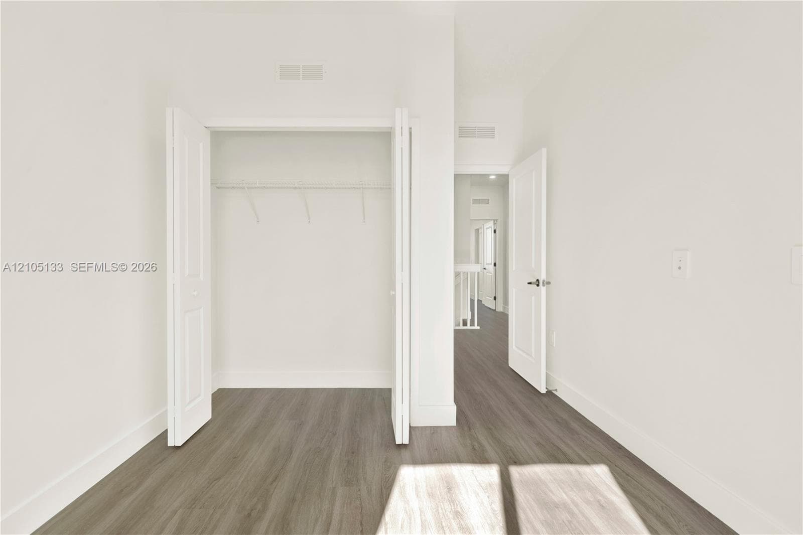 Wood-finish flooring throughout, bright white walls, and a convenient bi-fold closet
