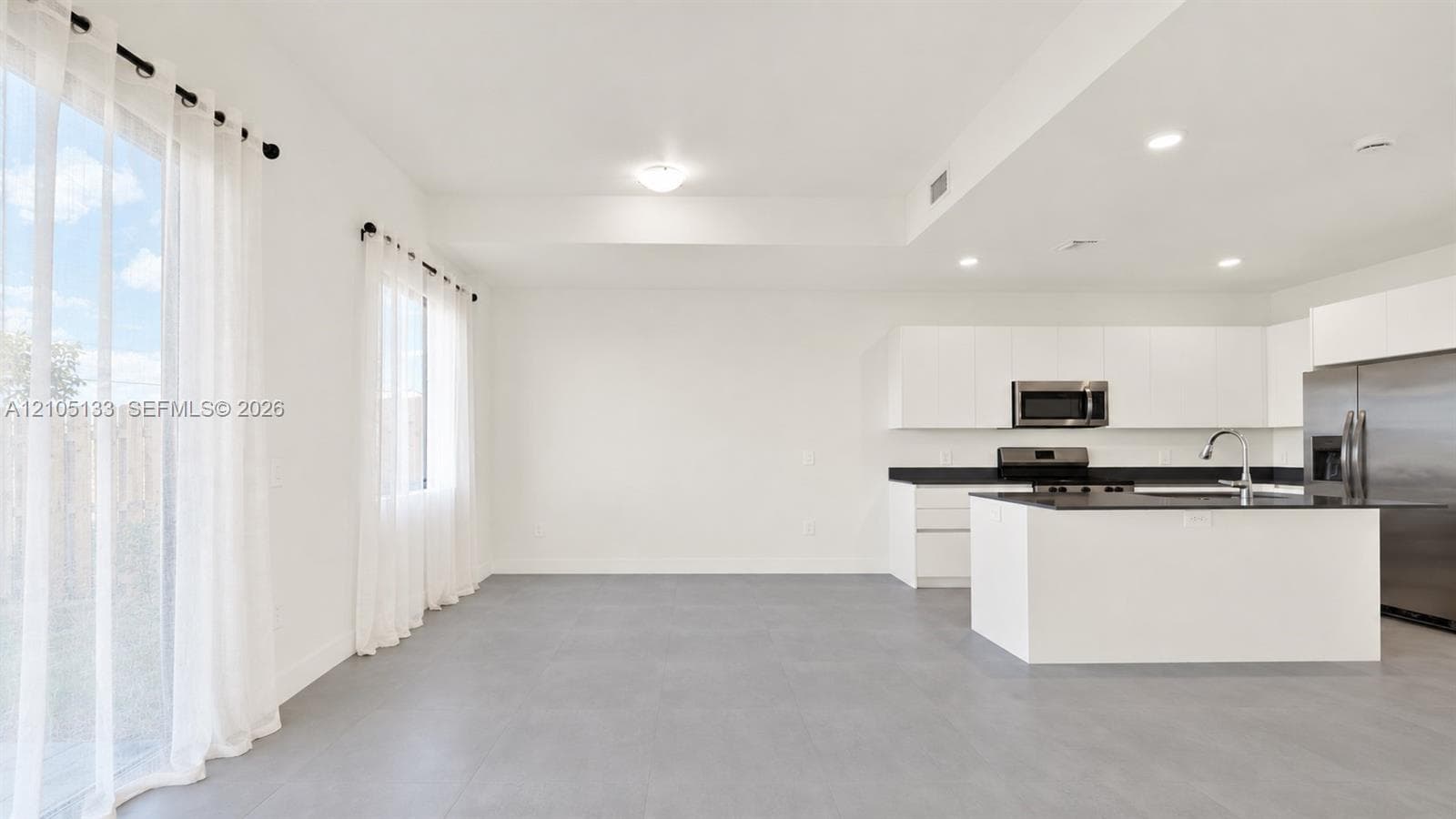 Open-concept living space with concrete-finish flooring, white walls, and recessed lighting