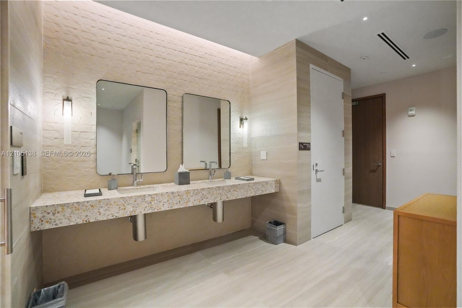 Floating double vanity with a speckled countertop, undermount sinks, and wall-mounted faucets