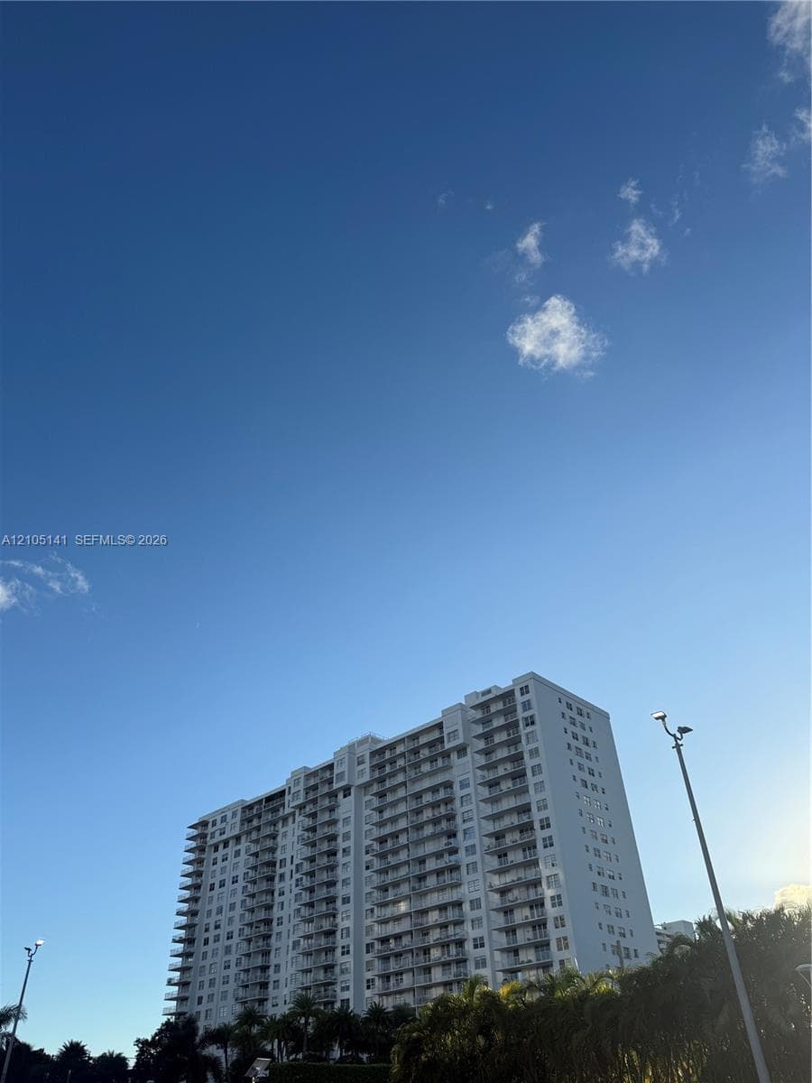 High-rise residential building featuring stacked private balconies and a light-toned exterior finish