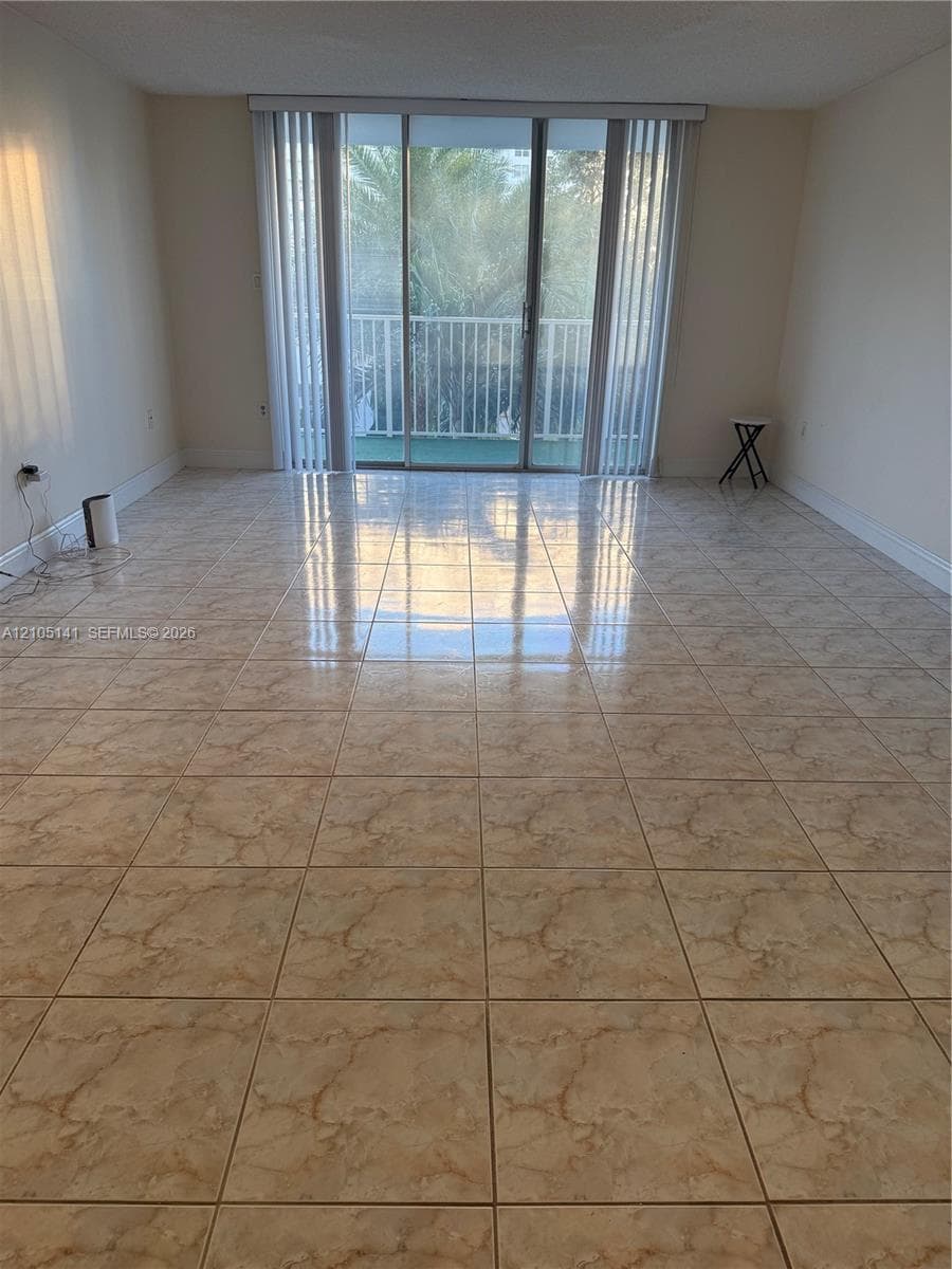 Interior space featuring large-format ceramic tile flooring, sliding glass patio doors, and vertical window blinds