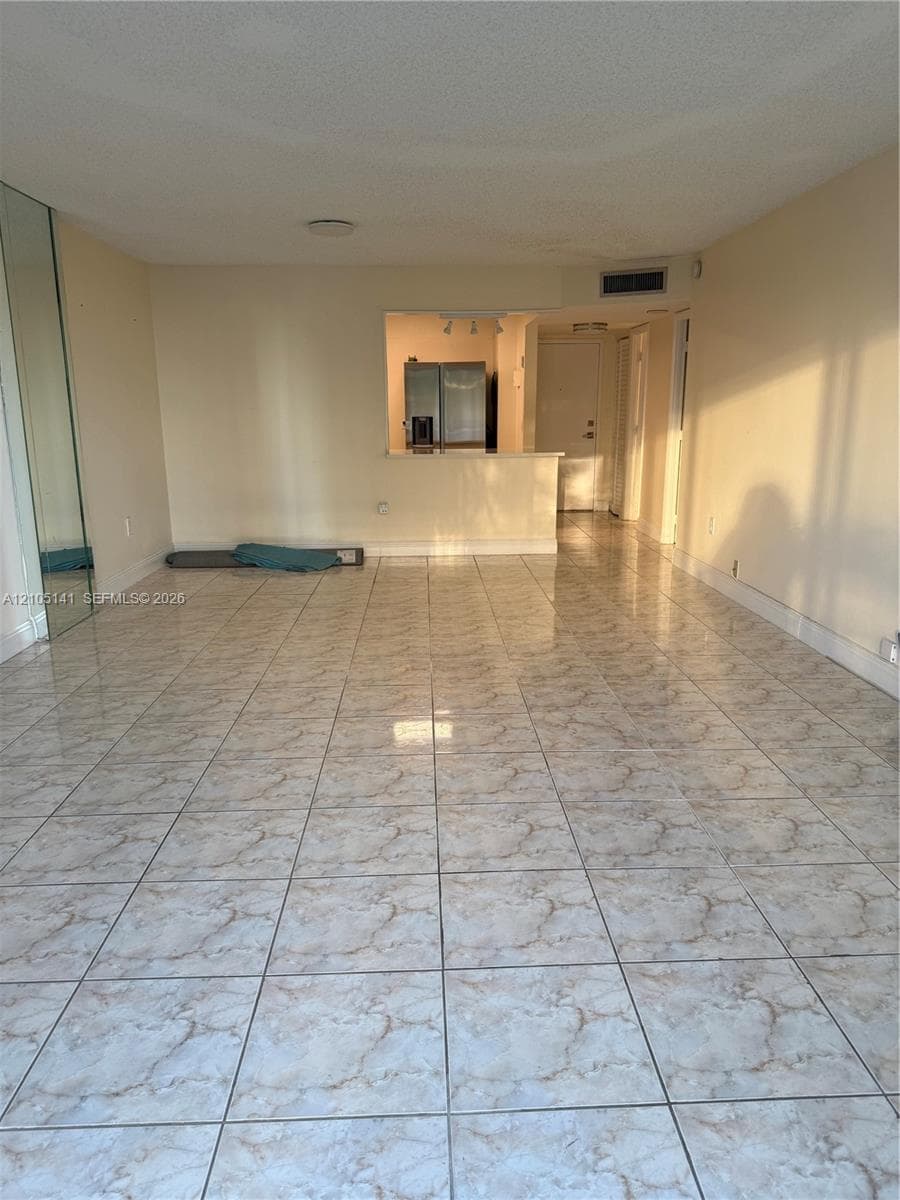 Large-format ceramic floor tiling throughout the living area, wall-to-wall mirrored panels, and a kitchen pass-through counter