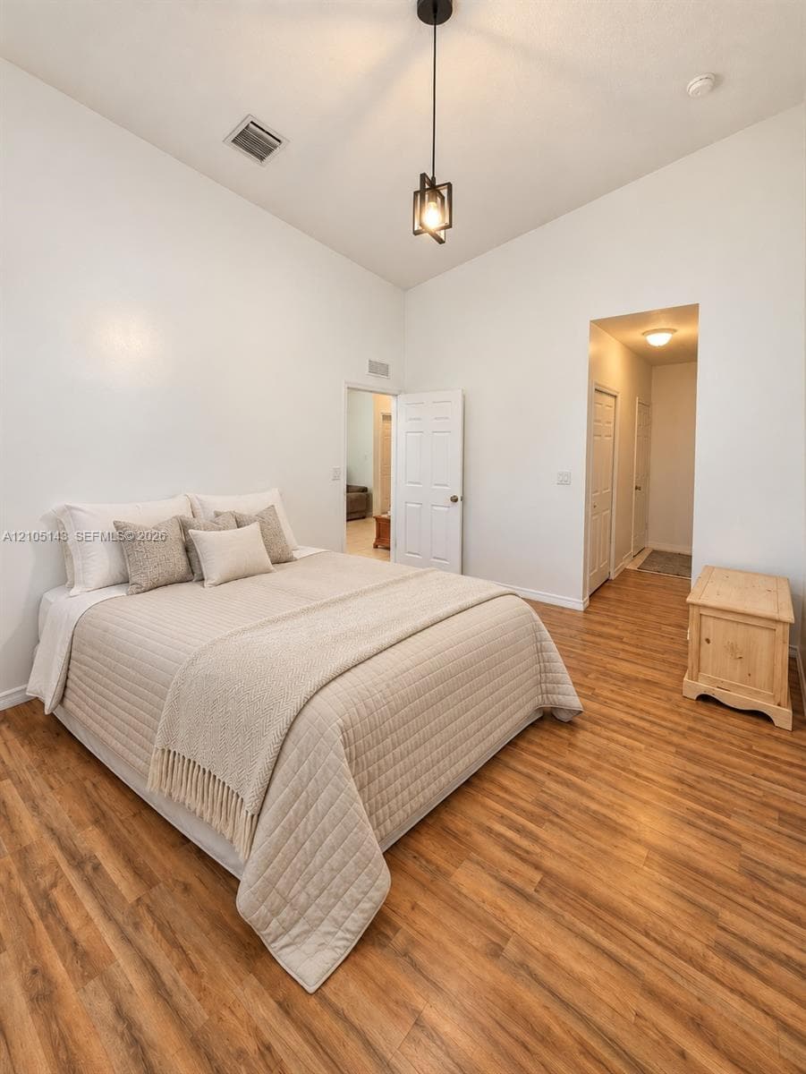 Vaulted ceilings with a suspended light fixture, wood-finish flooring, and white paneled doors
