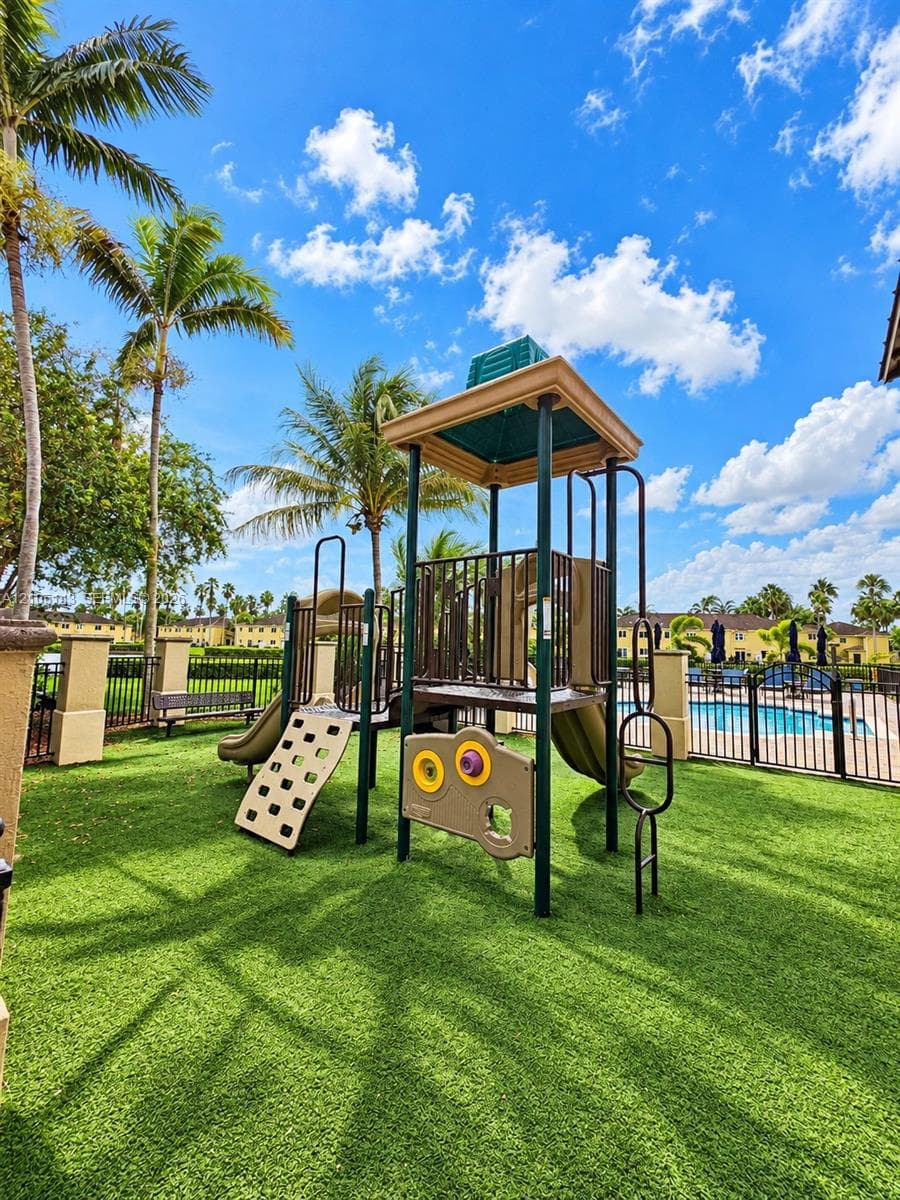 Playground featuring a climbing structure, slides, and turf surfacing