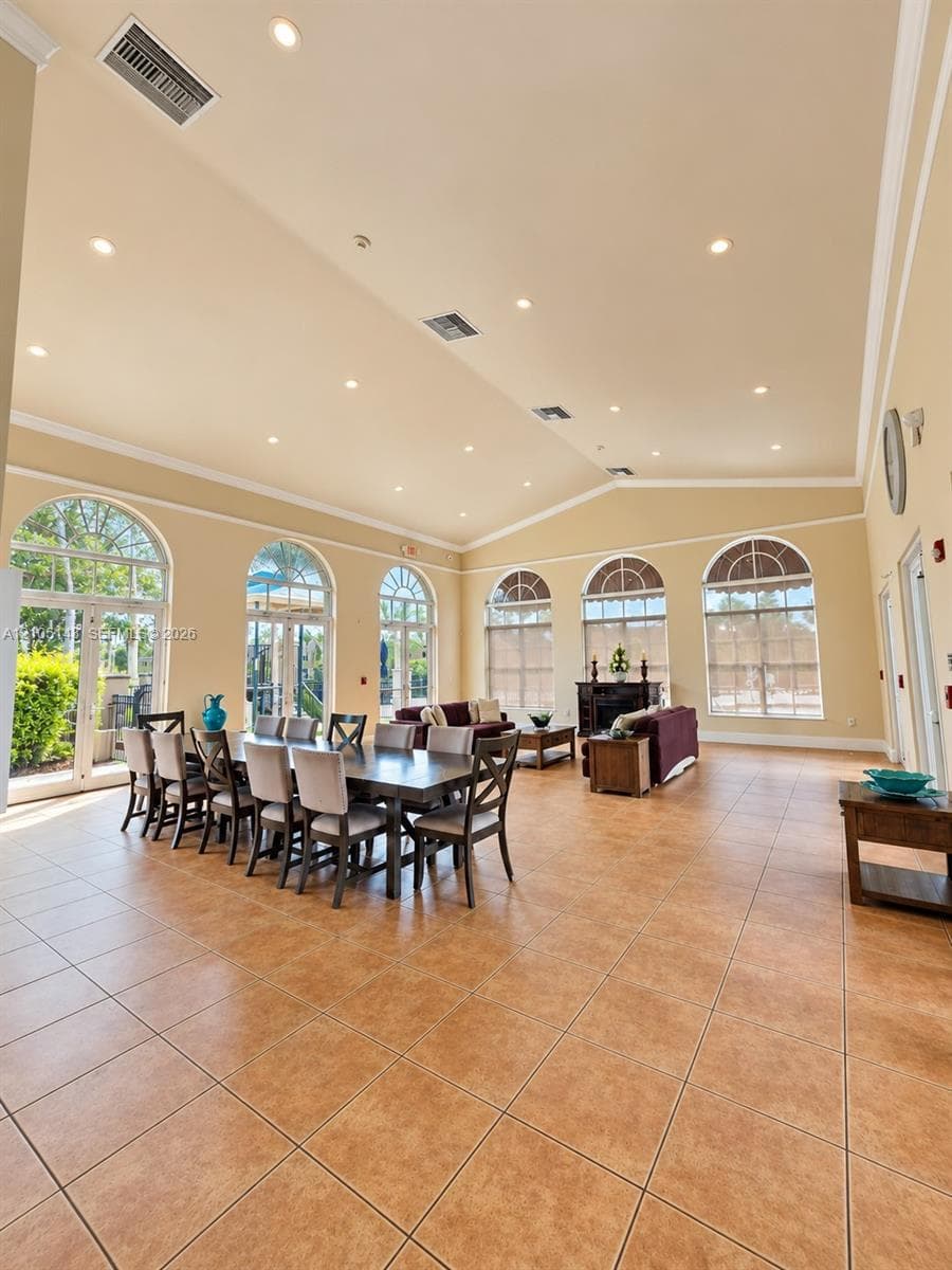 Spacious common area featuring large format tile flooring, vaulted ceilings, recessed lighting, and multiple arched windows