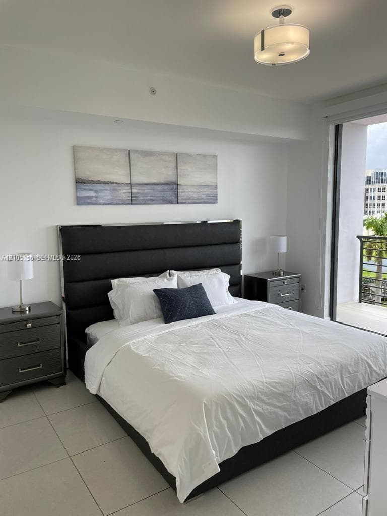 Large-format tile flooring, drum-style ceiling light fixture, and floor-to-ceiling glass door leading to a private balcony