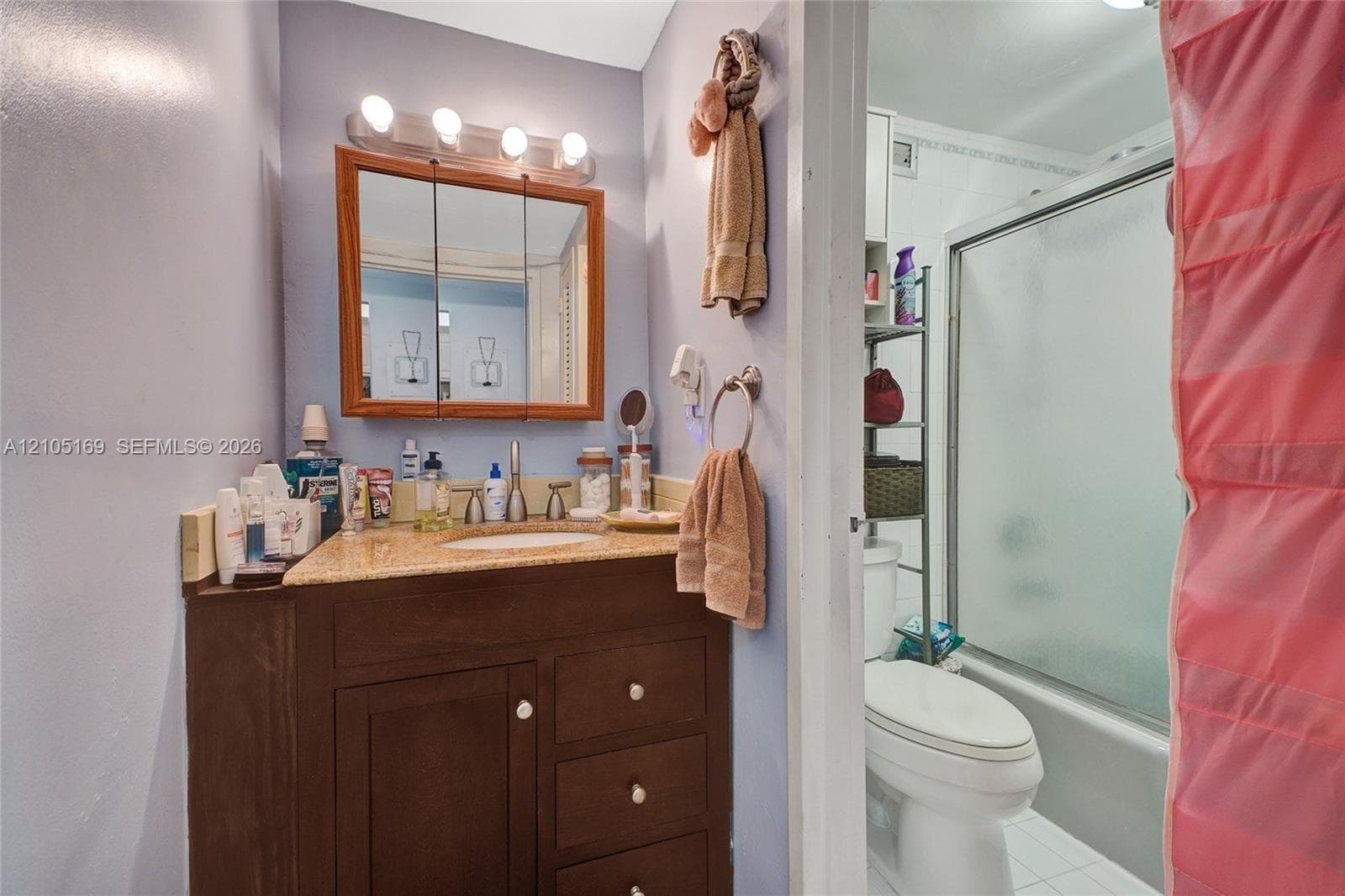 Bathroom featuring a wood-finish vanity with an integrated sink and light-toned countertop