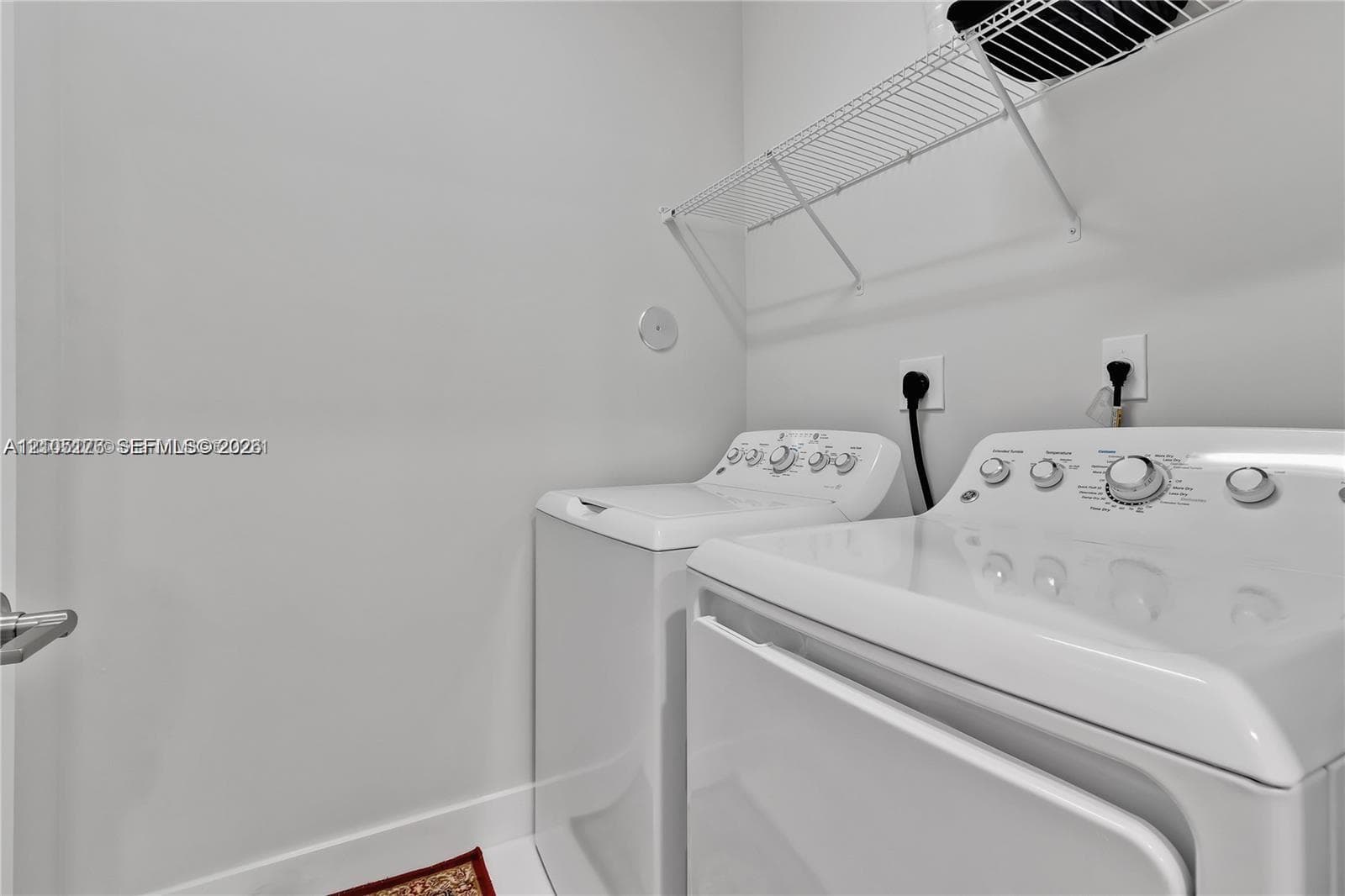 Laundry area featuring white top-load appliances and overhead wire shelving