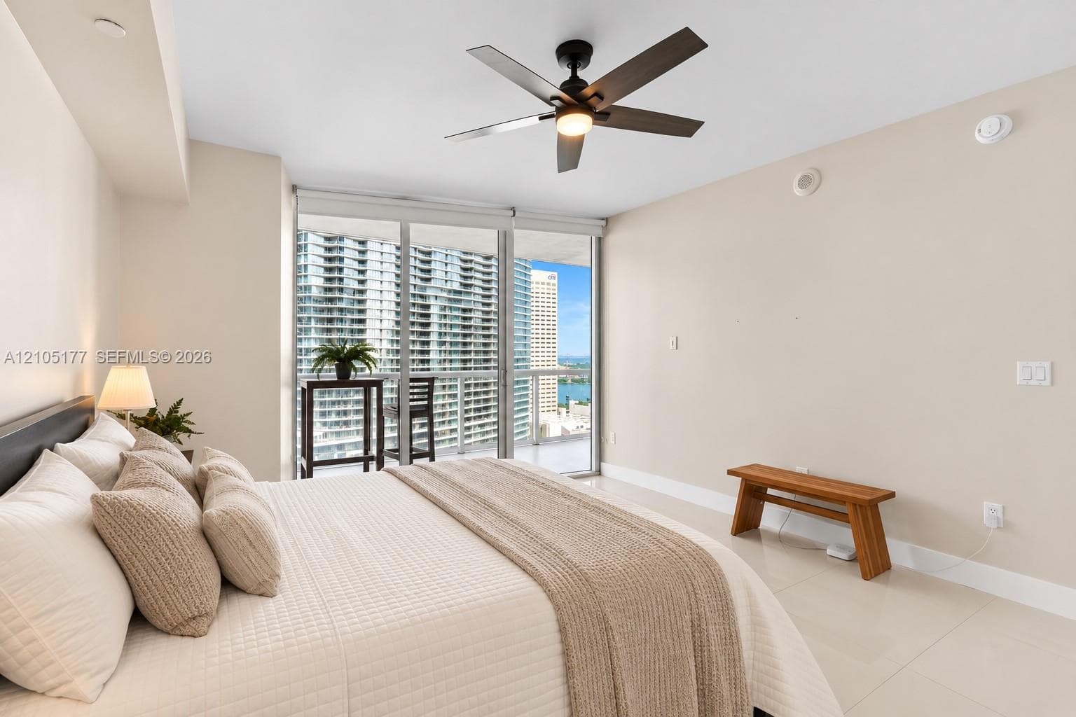 Floor-to-ceiling glass sliding doors, polished tile flooring, ceiling fan with integrated lighting, and access to a private balcony