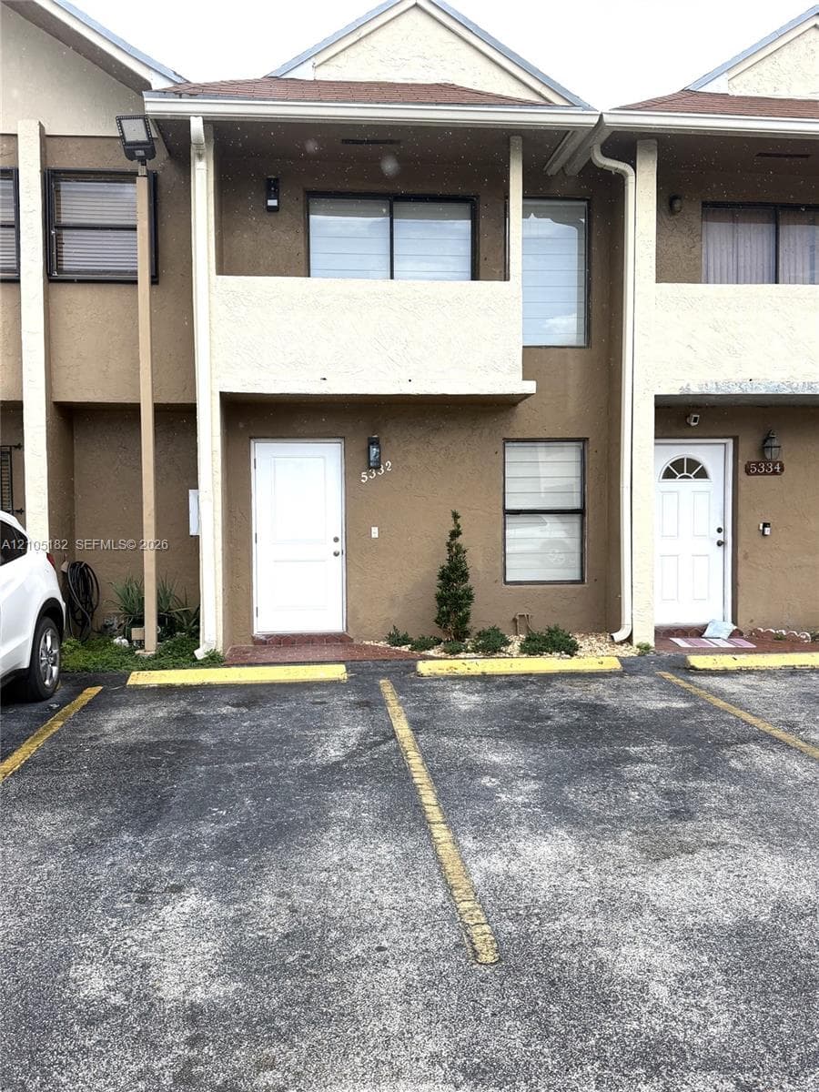 Two-story exterior with a second-floor balcony, white entry door, and integrated parking