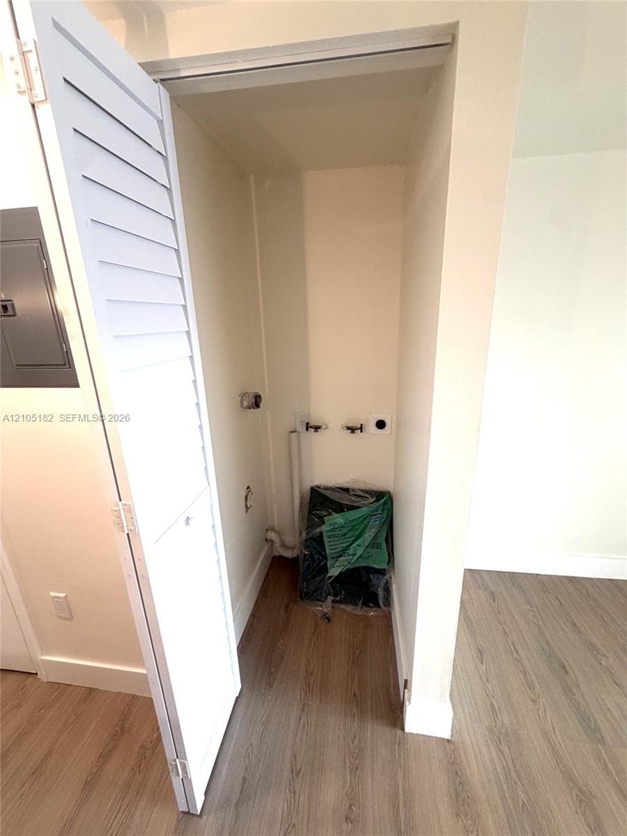 Dedicated laundry closet with bi-fold louvered doors and wood-finish flooring