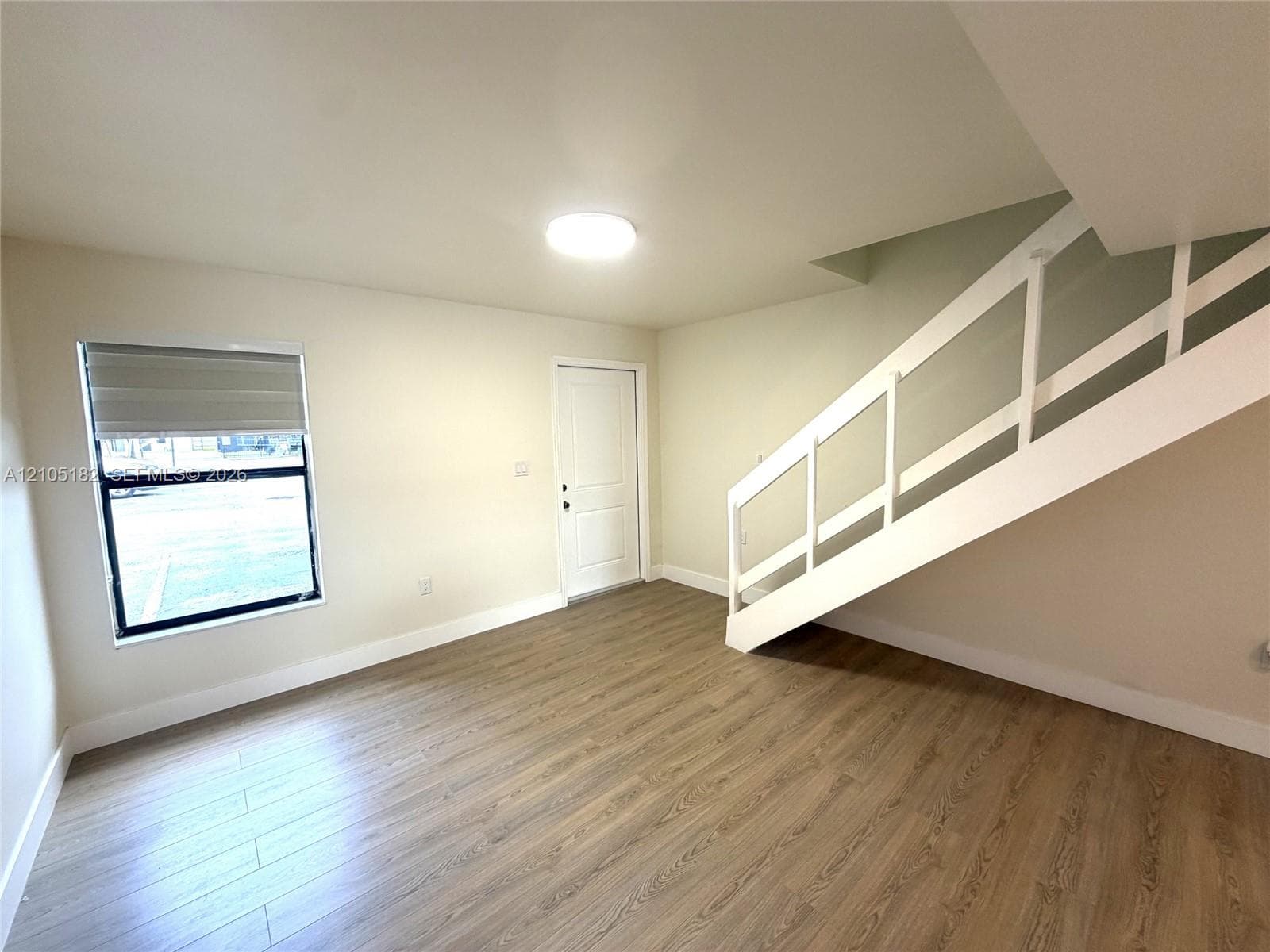 Open-concept living area featuring wood-finish flooring and a staircase with a white railing