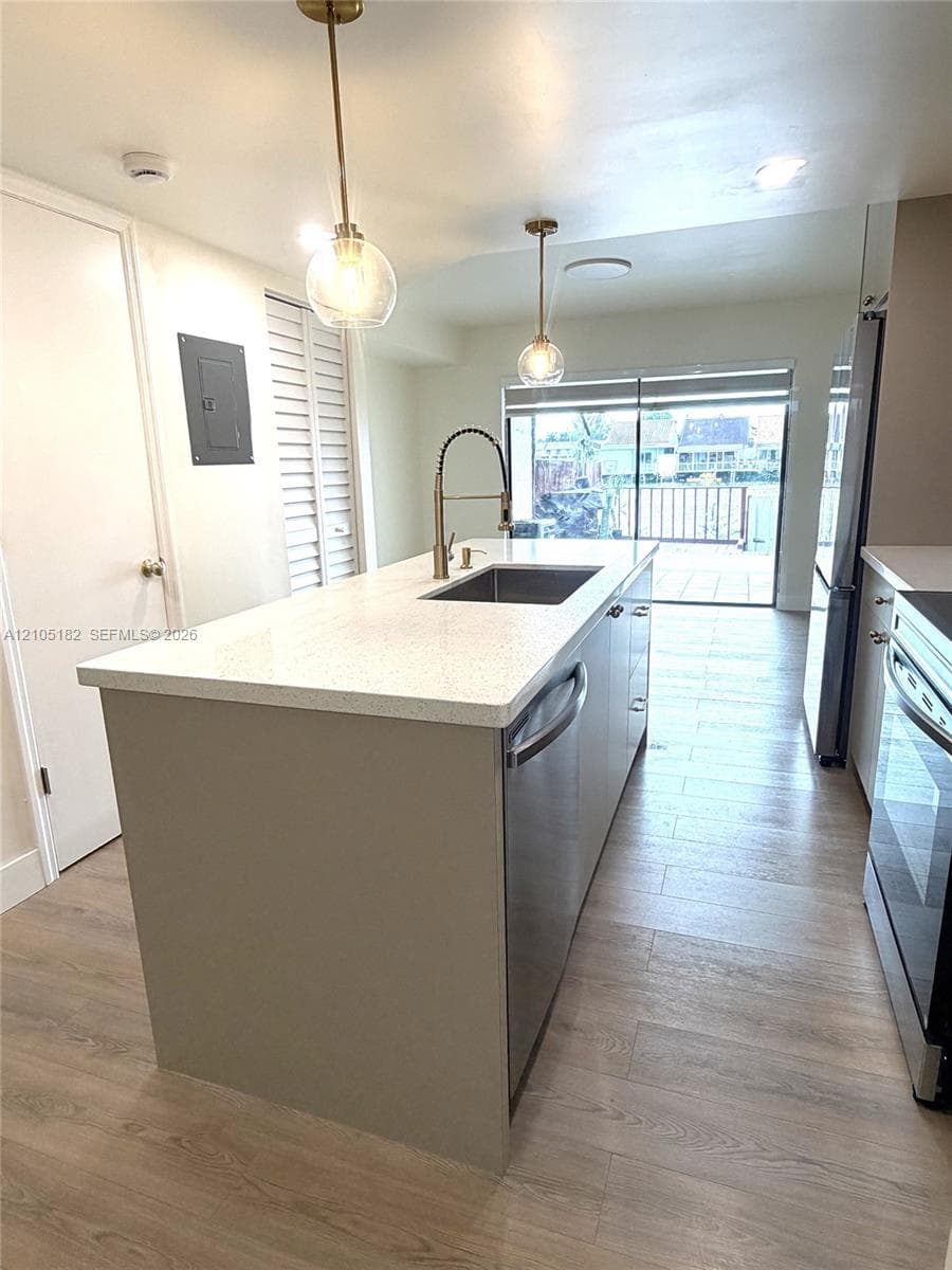 Kitchen island featuring a single basin sink, gooseneck faucet, and integrated dishwasher
