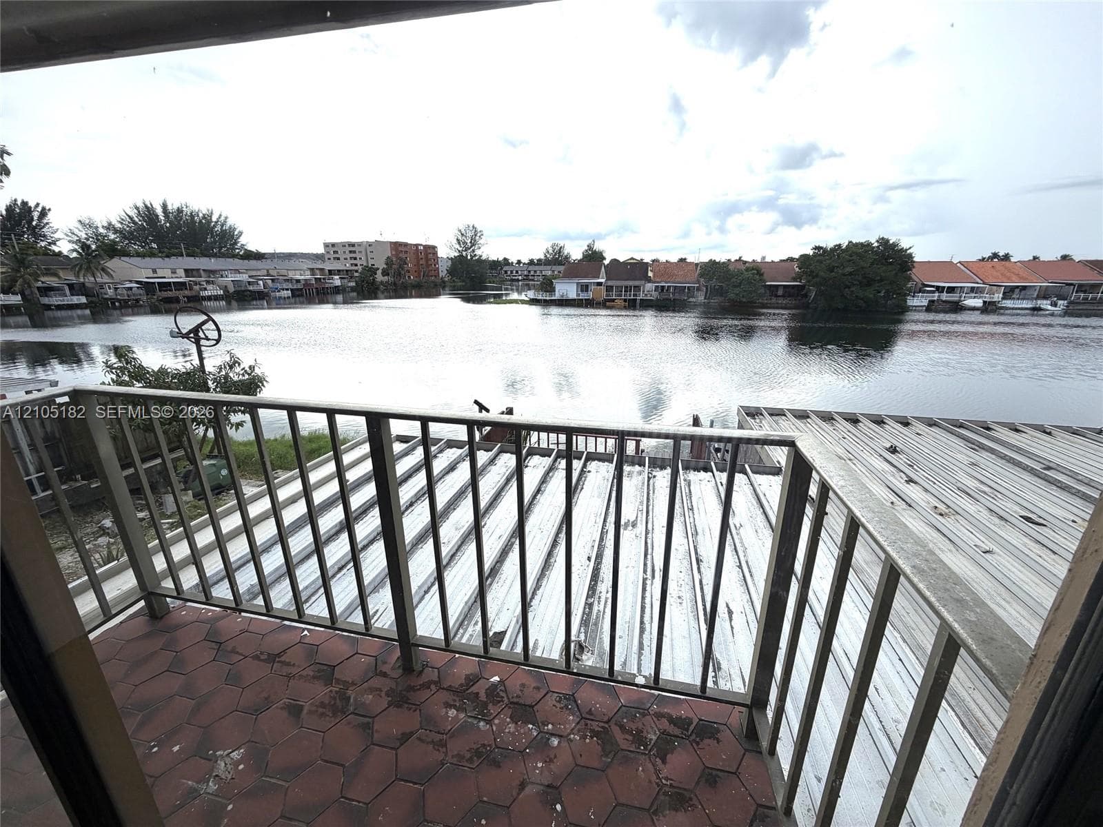 Balcony with hexagon-patterned tile flooring and metal railing overlooking a body of water