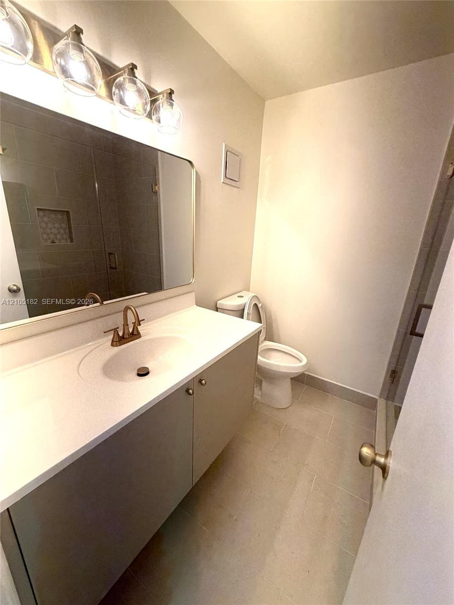 Single vanity with integrated sink, light-toned countertop, and bronze-finish faucet