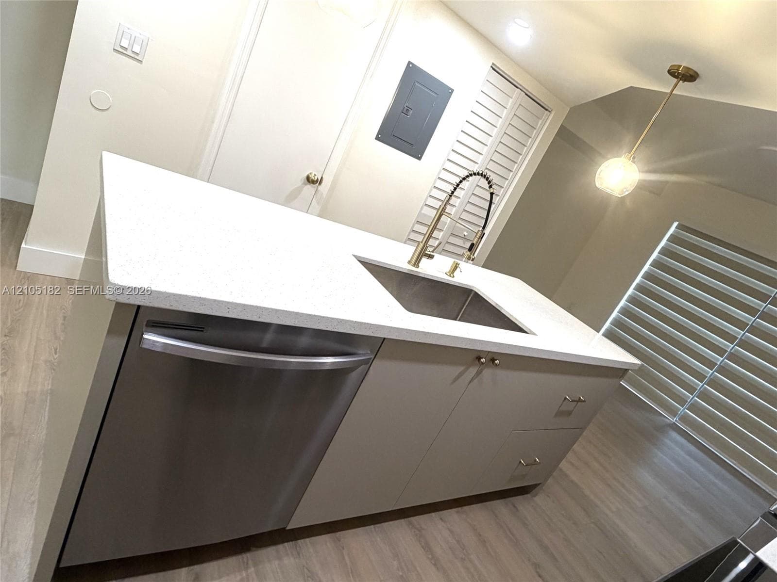 Kitchen island featuring a stainless steel sink, gold-finish faucet, and integrated stainless steel dishwasher