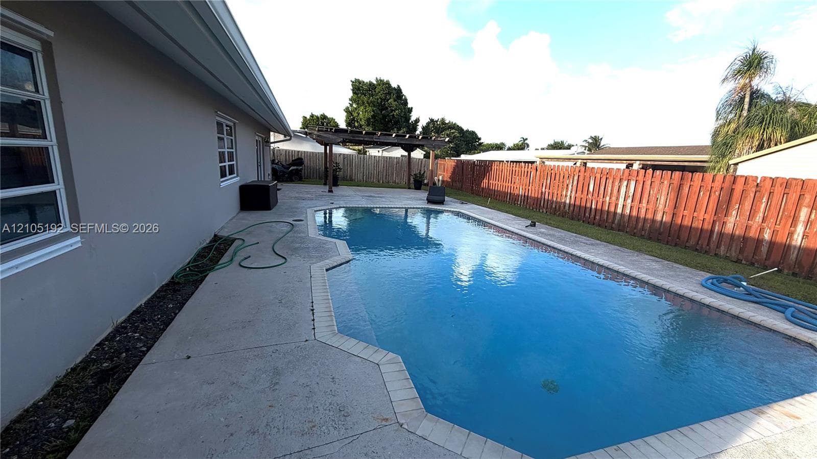 Rectangular swimming pool with integrated spa, bordered by concrete decking and a wood privacy fence