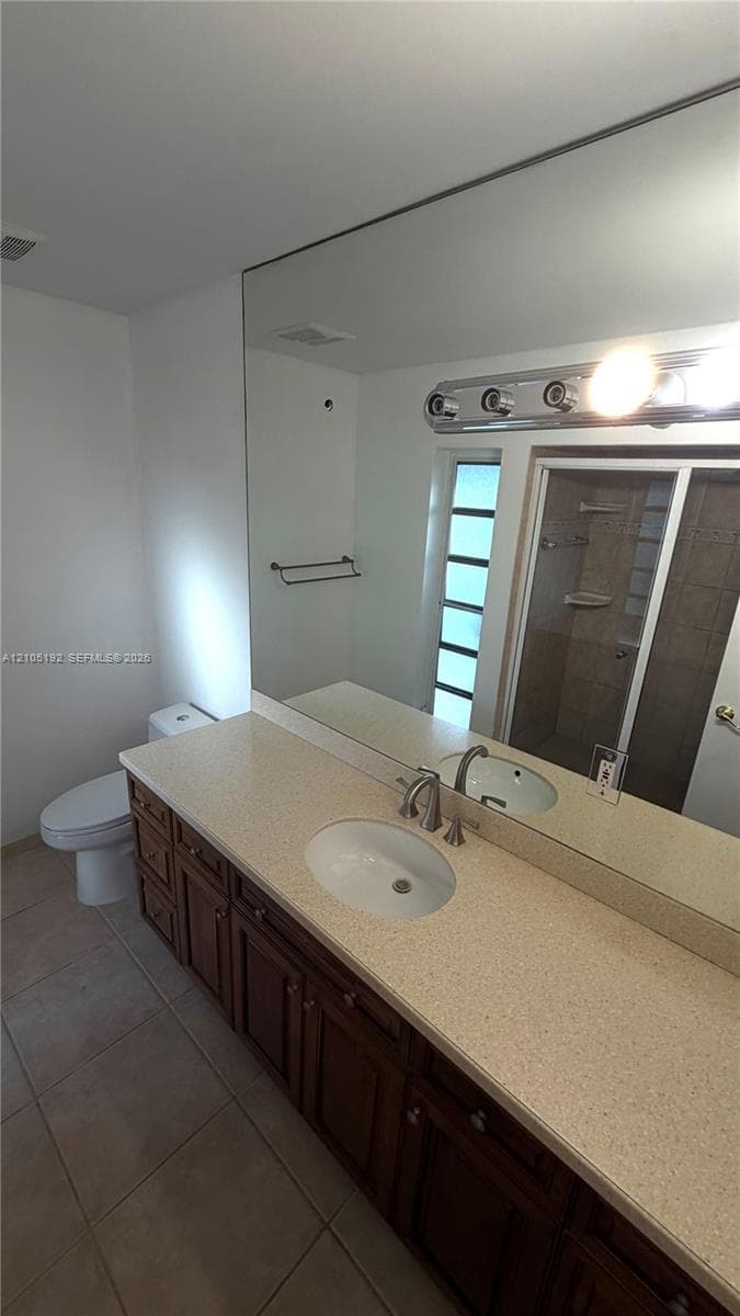 Extended vanity featuring dual integrated sinks with brushed nickel fixtures, a light-toned countertop, and dark wood-finish cabinetry